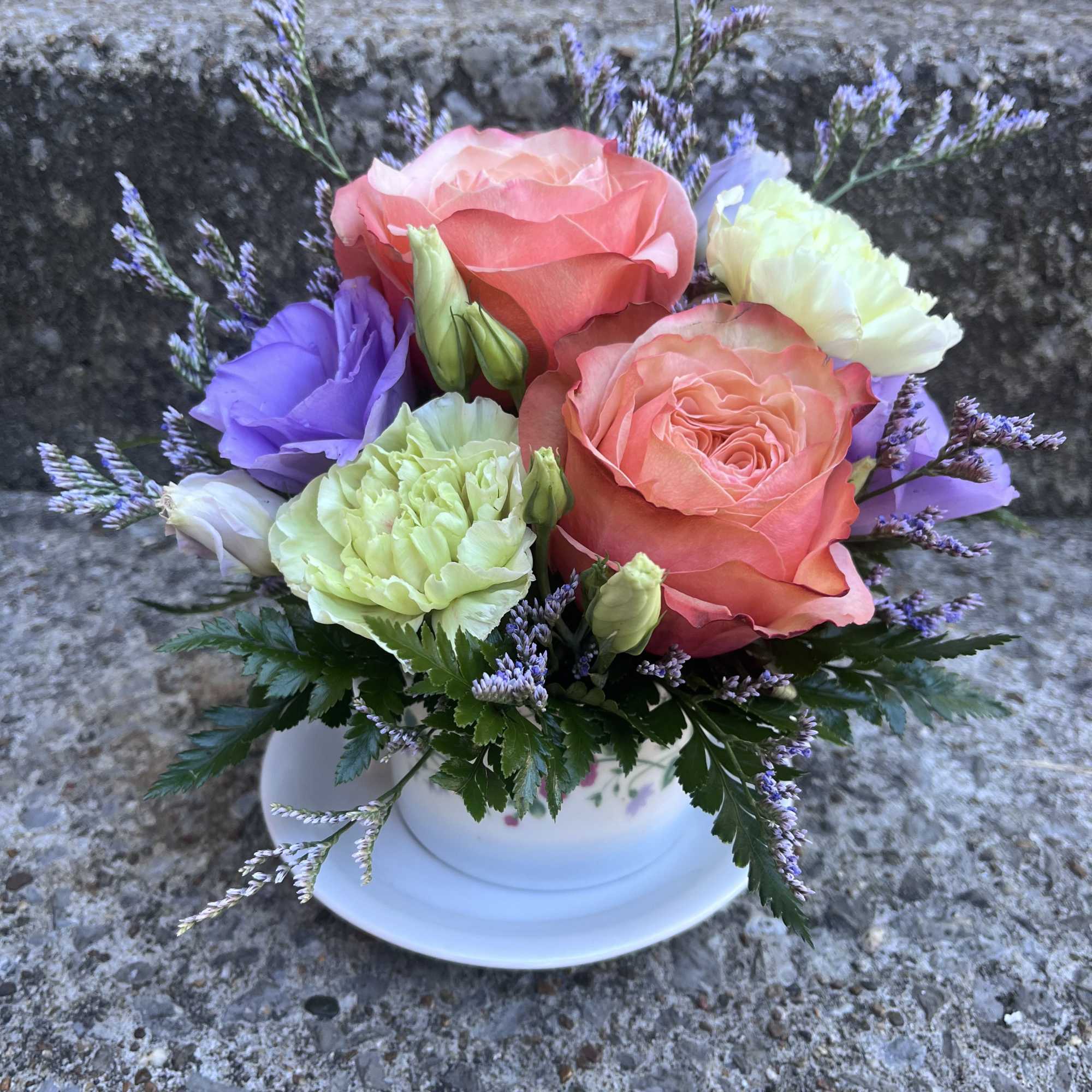 This arrangement has roses , limonium , lisianthus, carnations and greenery.