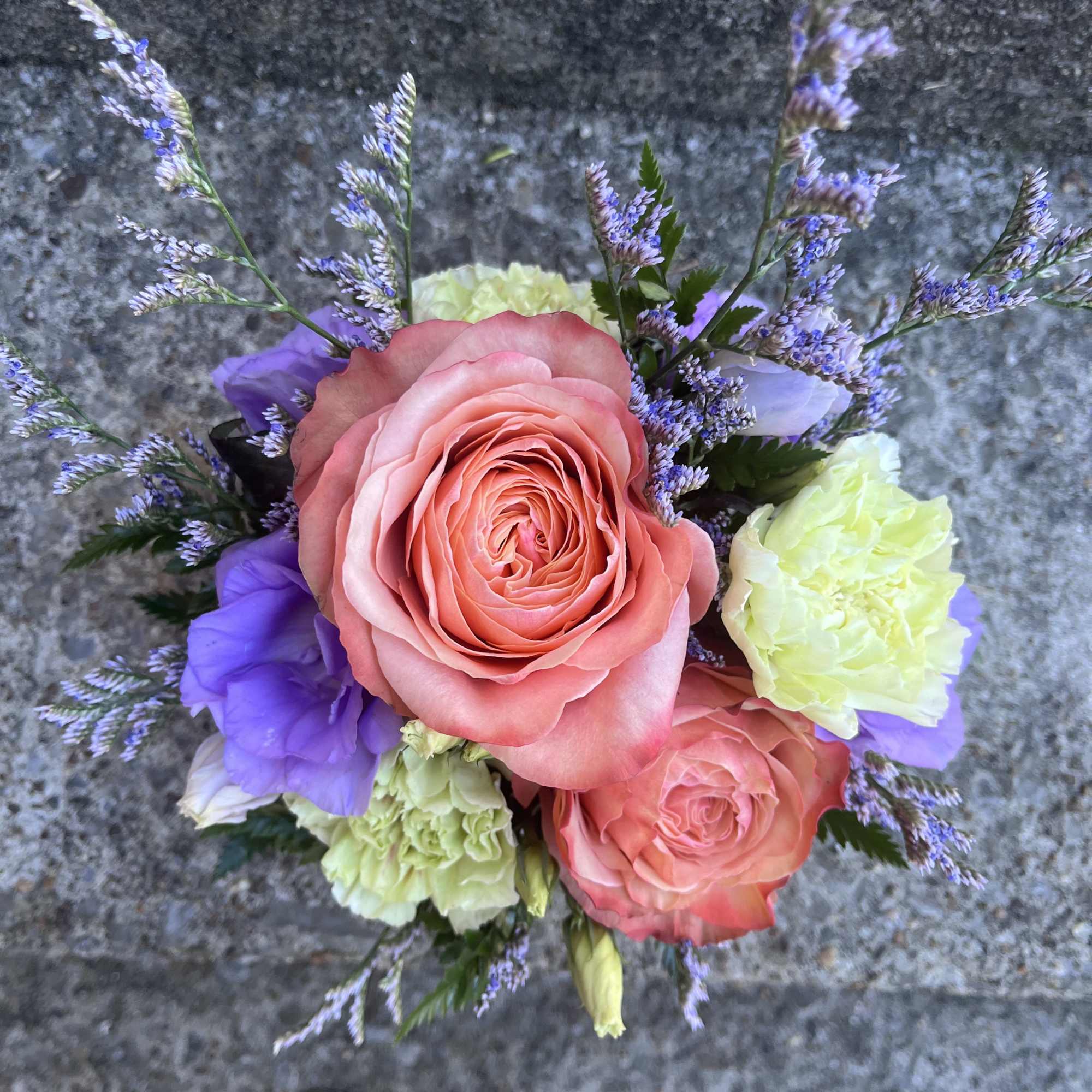 This arrangement has roses , limonium , lisianthus, carnations and greenery.