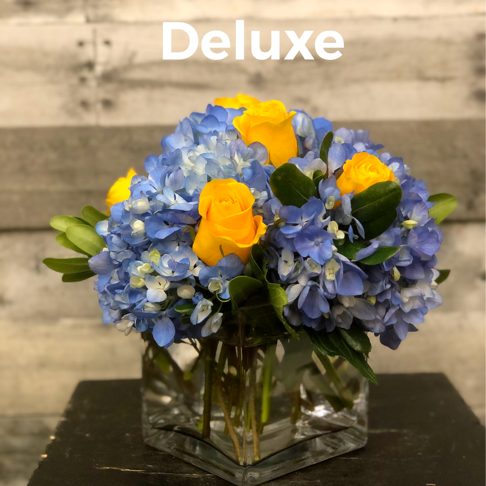 Glass cube vase with blue hydrangea and yellow roses.  Due to