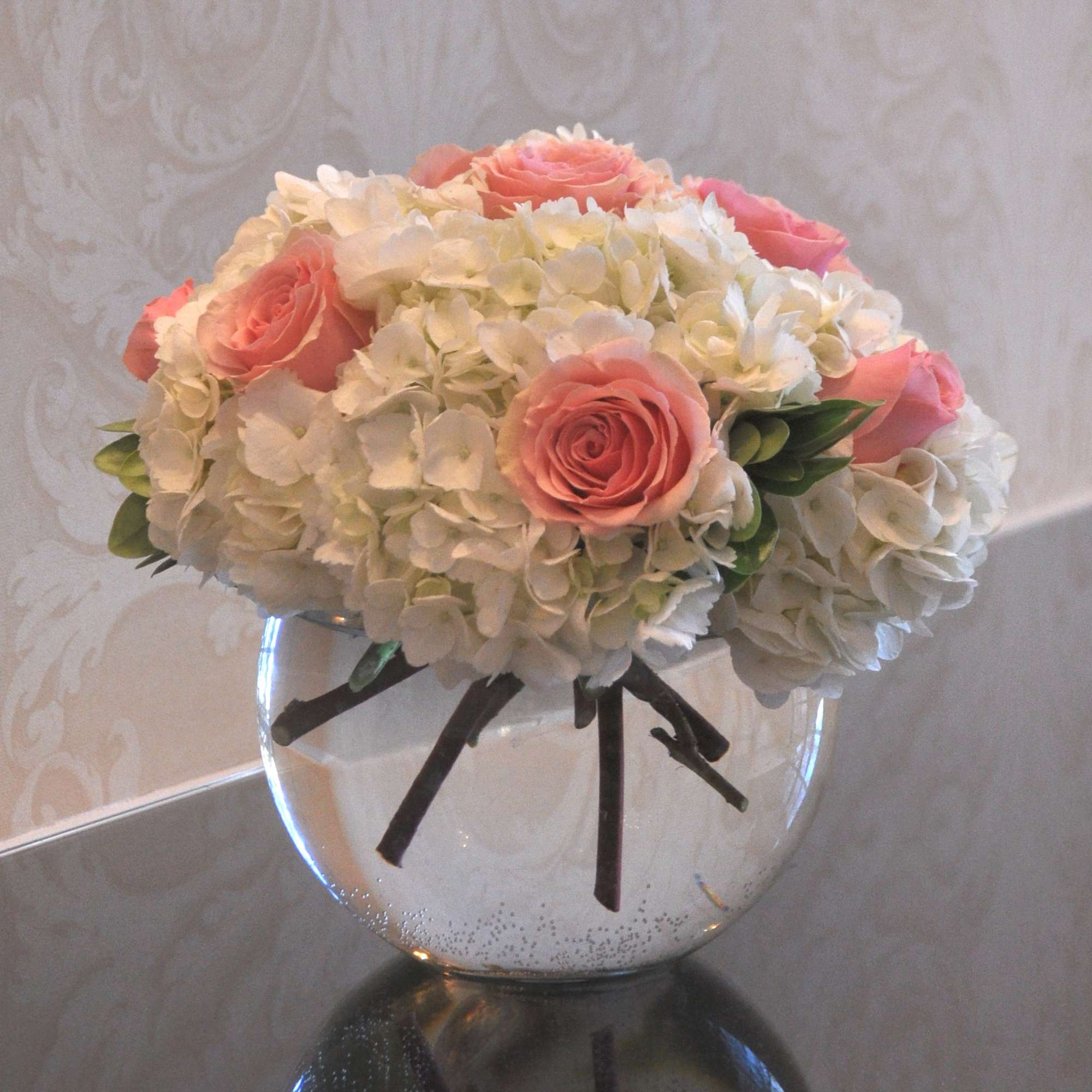 A glass bubble bowl filled with hydrangea and roses. Classic and elegant.