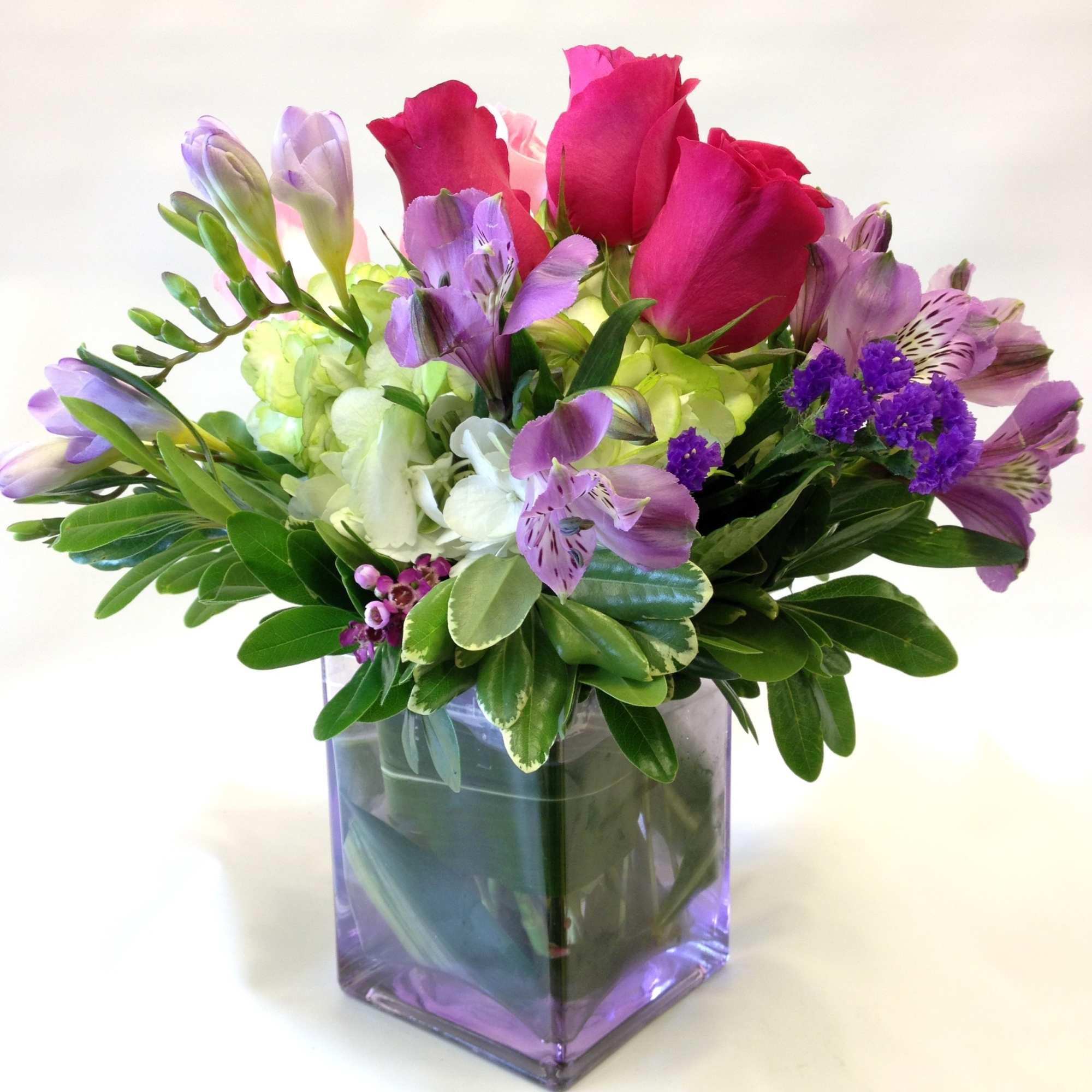 Lovely freesia, roses, alstromaria lilies and hydrangea fill a pastel glass cube