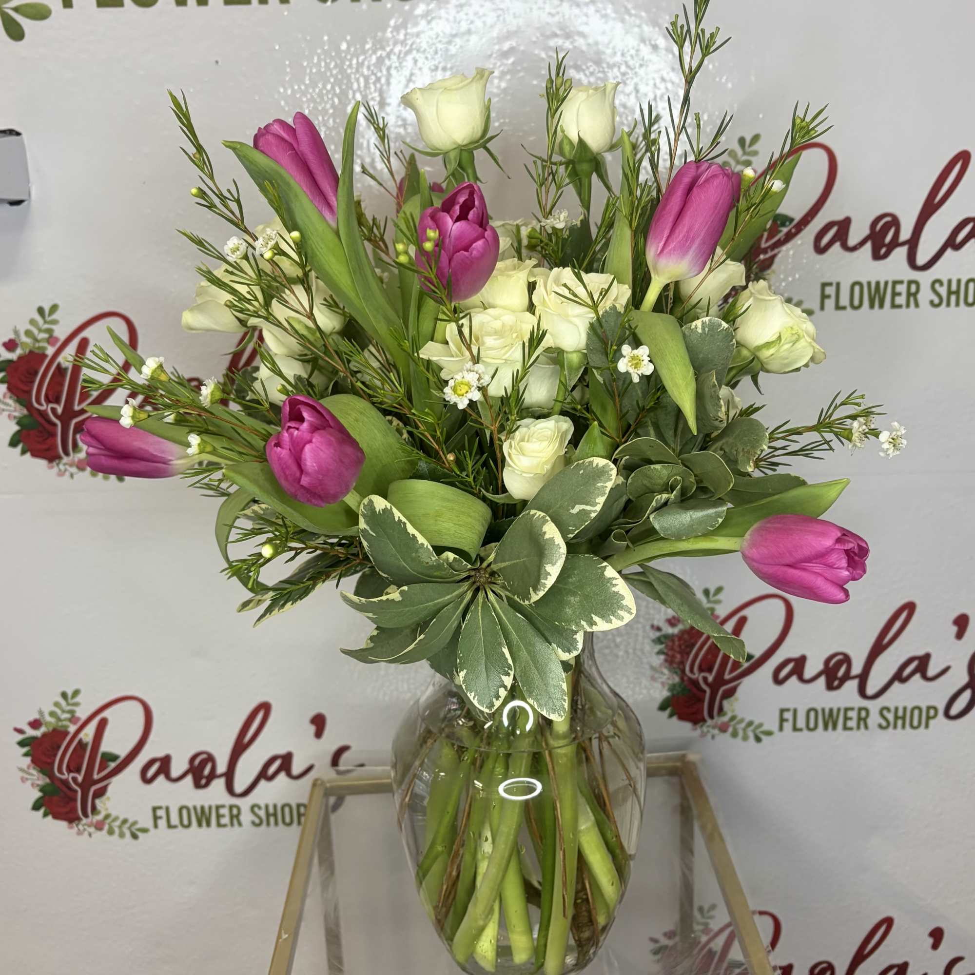 A graceful vase arrangement featuring fresh pinky tulips*, creamy white spray roses