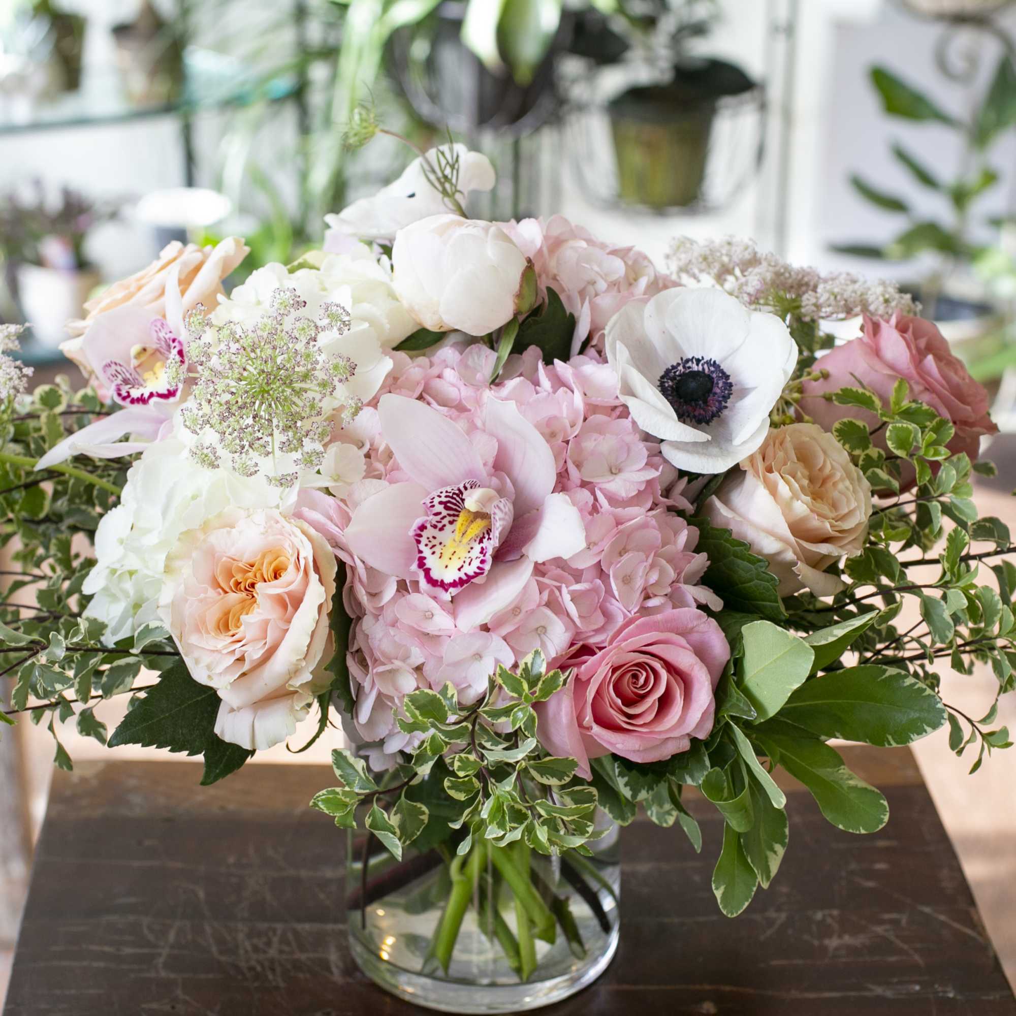 Monochromatic light pink flowers along with designer roses, arranged in a clear