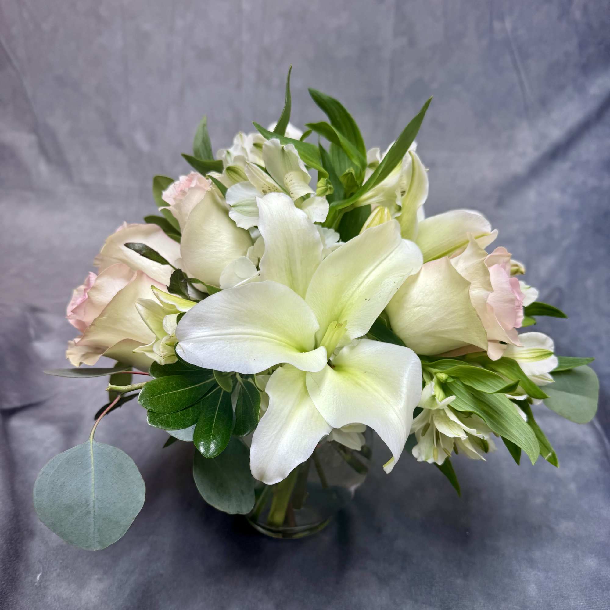 A delicate arrangement of white lilies , white alstroemeria ,and fresh pink