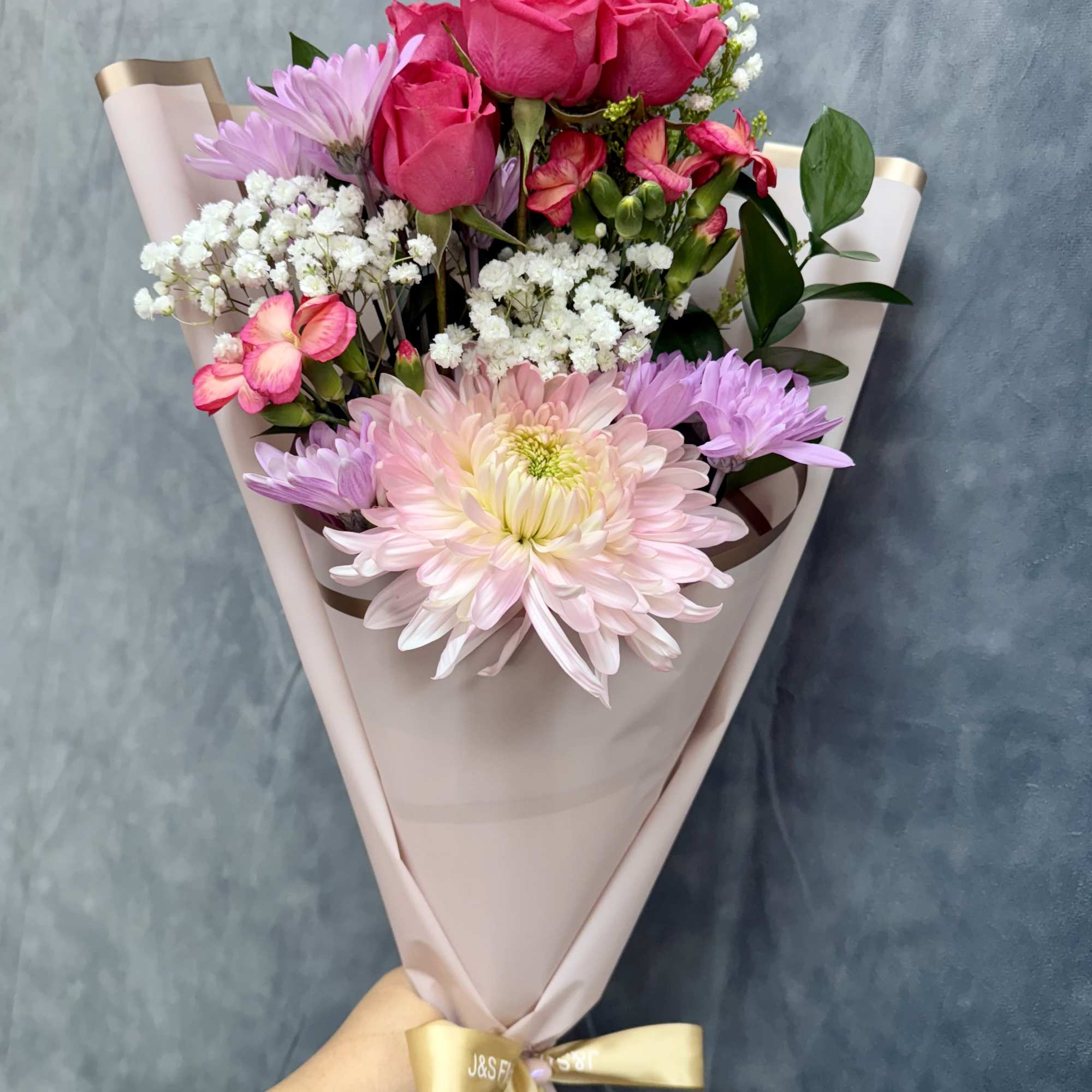 Our petite Pink Breeze hand-tied bouquet features cheerful mums, spray roses, daisies