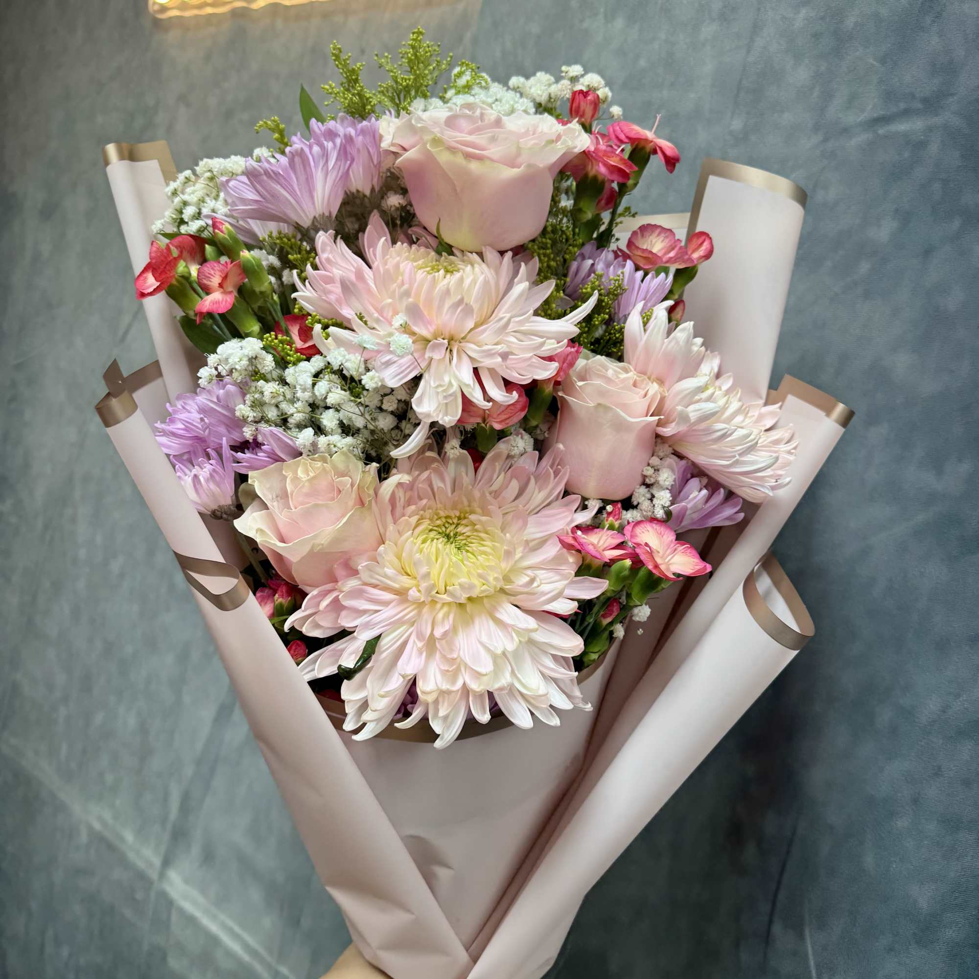 Our petite Pink Breeze hand-tied bouquet features cheerful mums, spray roses, daisies
