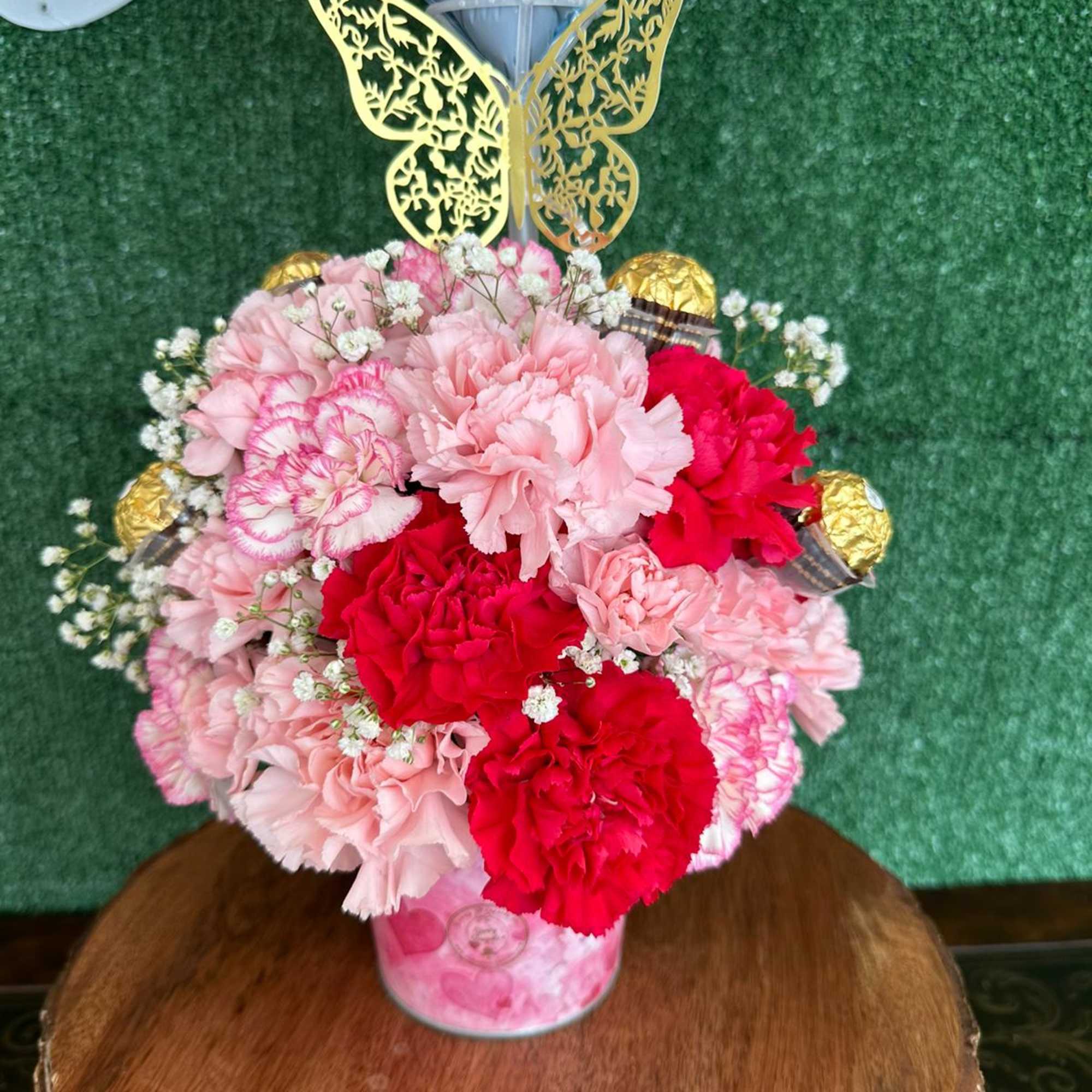 Carnations and baby breath on a pink bucket with chocolates and custom