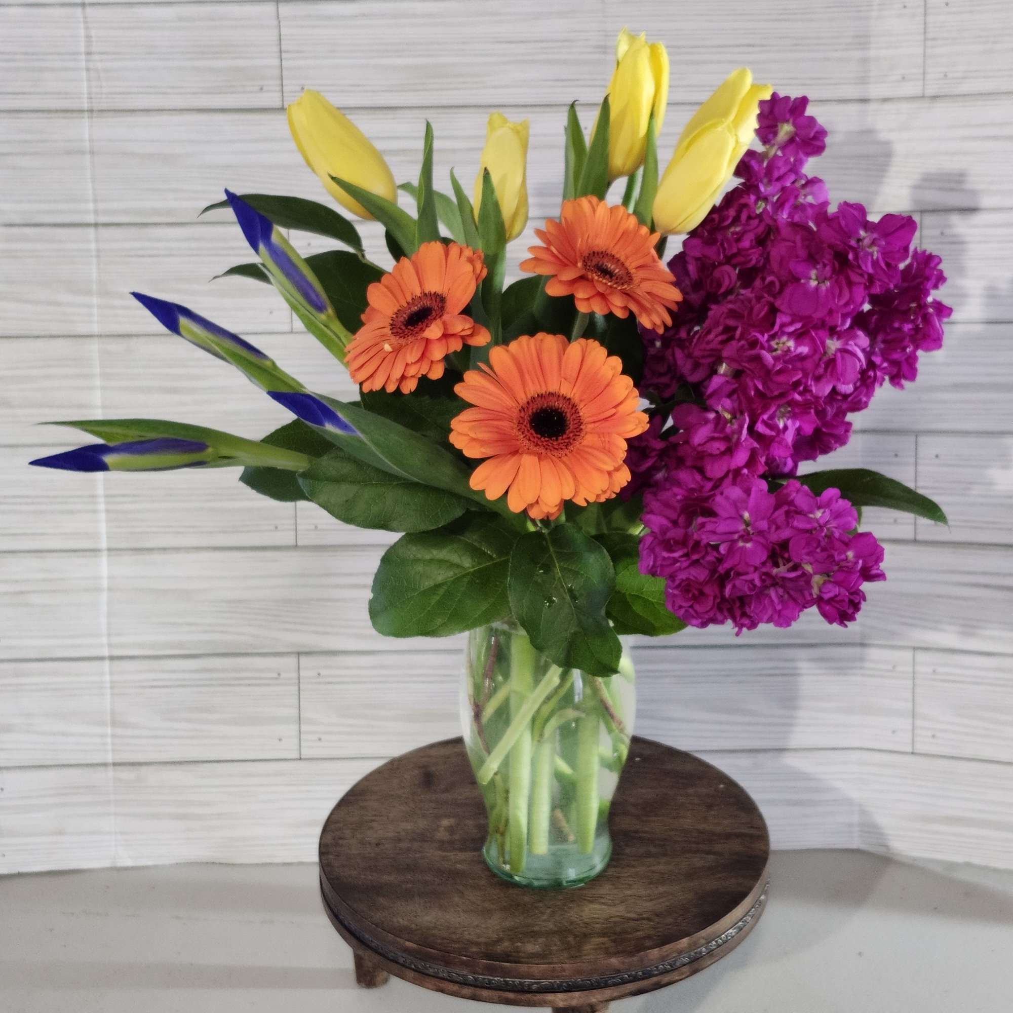 Featuring daisies, tulips, iris, and stock this petite arrangement is a fun