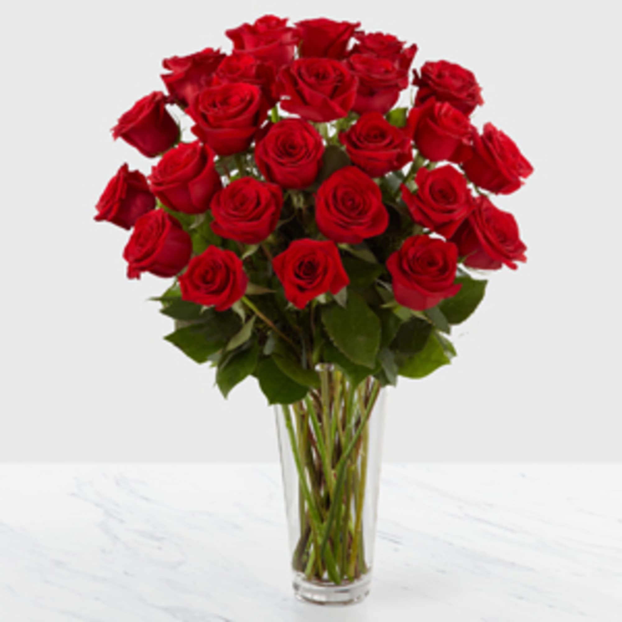 Romantic red roses are arranged in a sparkling glass vase, and accented