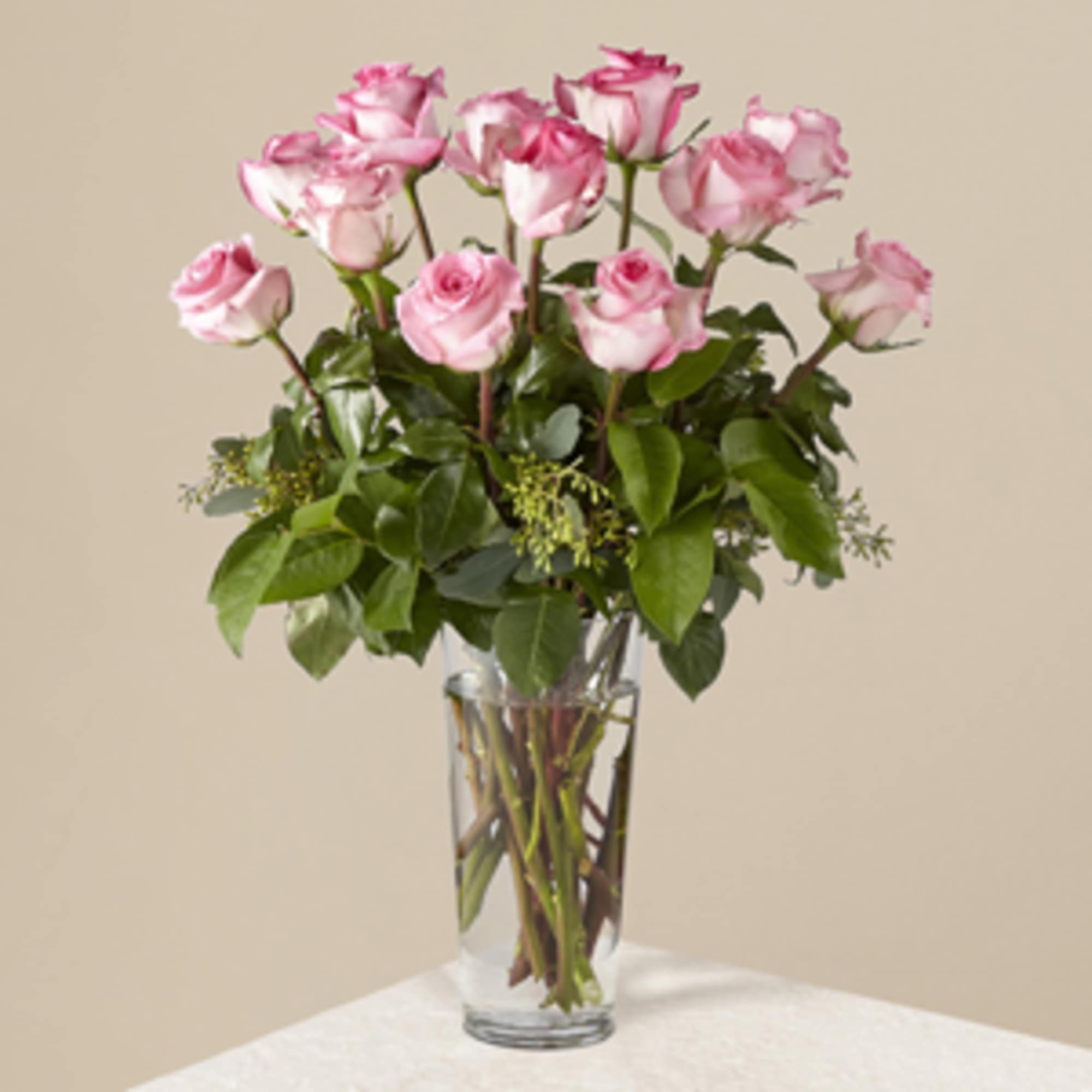 Pink roses are arranged in a sparkling glass vase, and accented with
