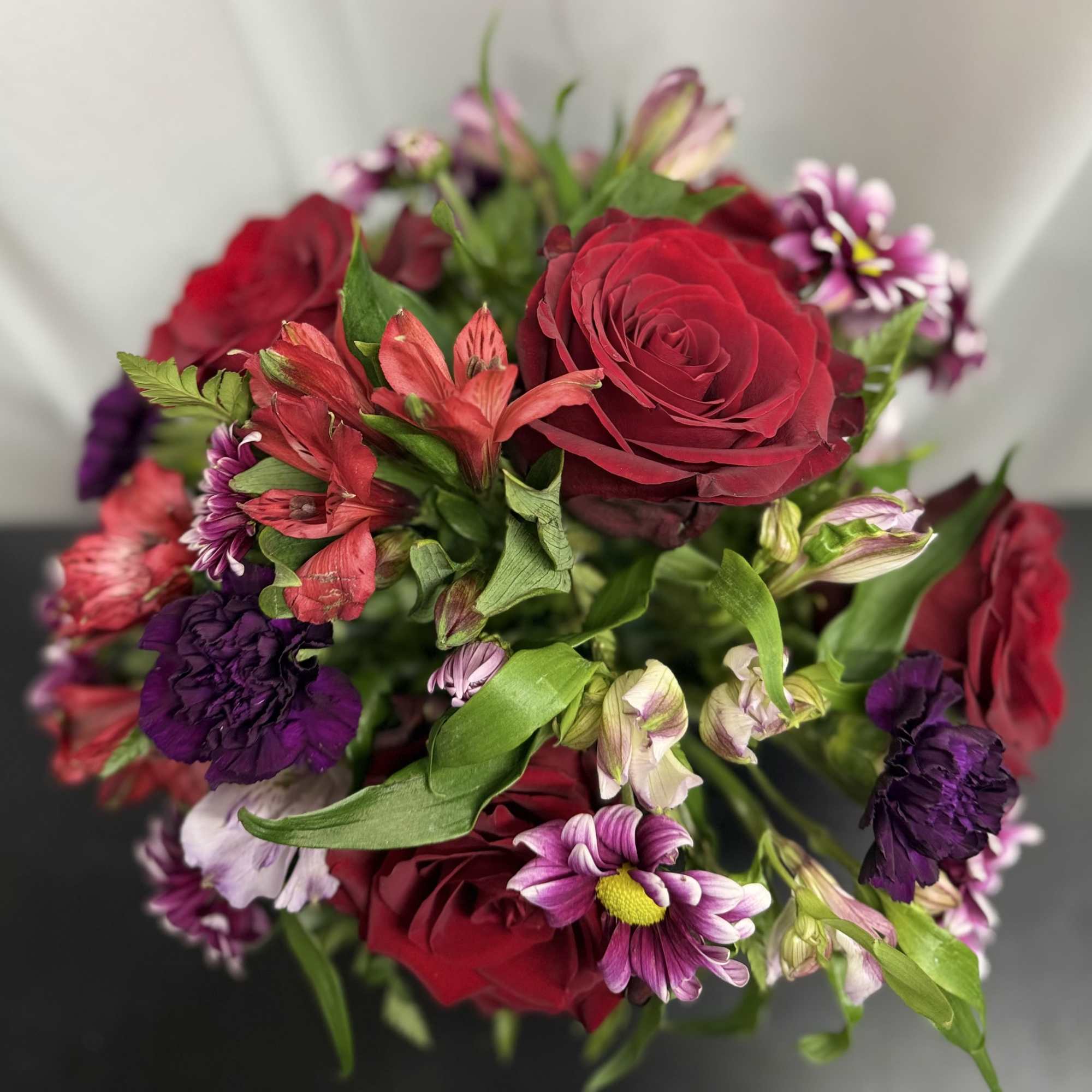 Our premium Red Explorer roses, deep plum Moon Vista carnations with a