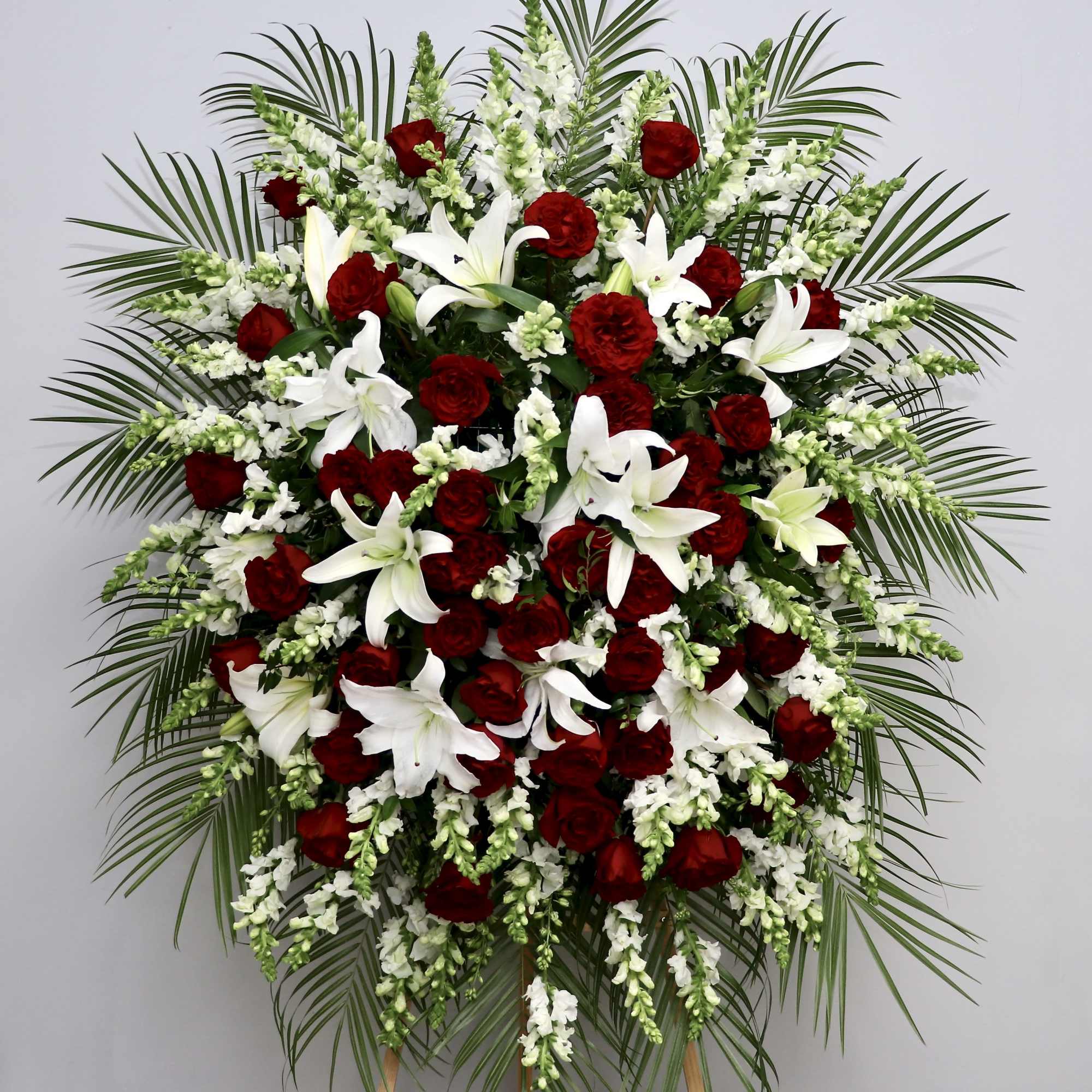 This spray combines red roses, lilies, and snapdragons to create an elegant