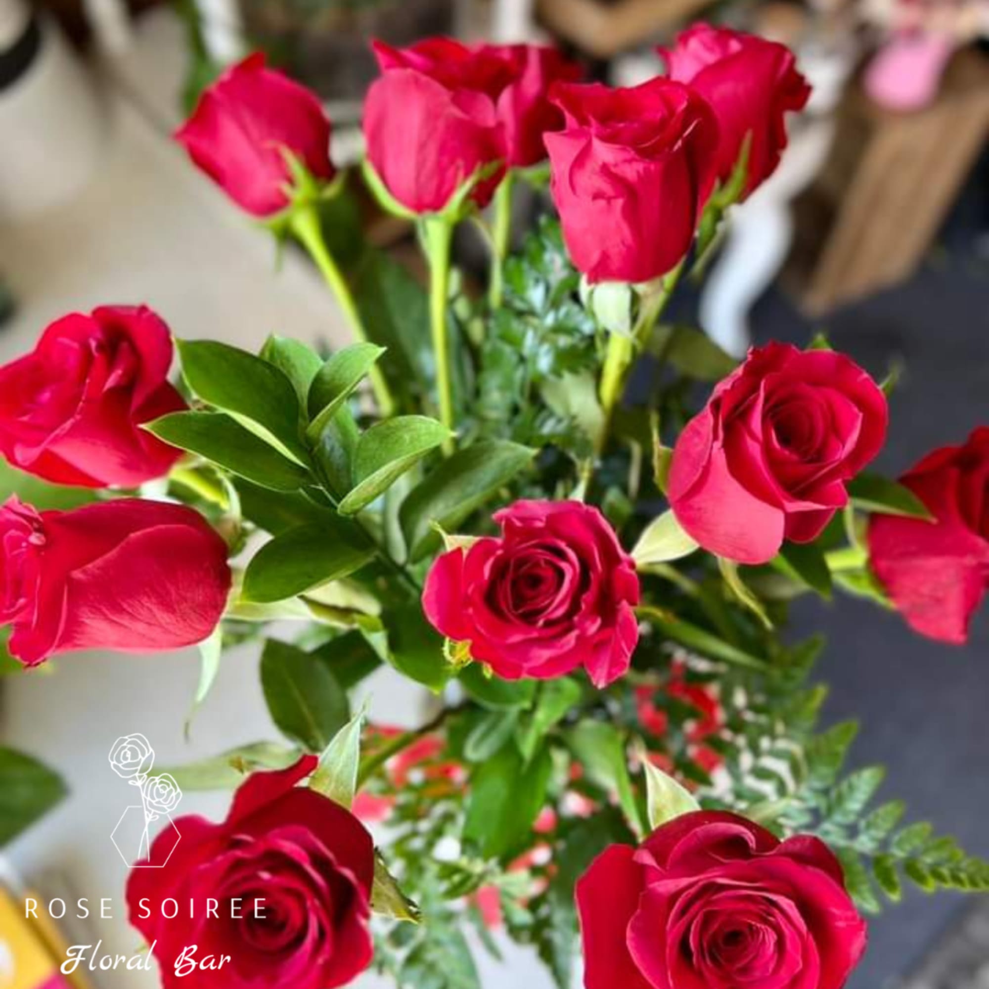 Vibrant red Rose's arranged with mixed foliage and greenery in a glass