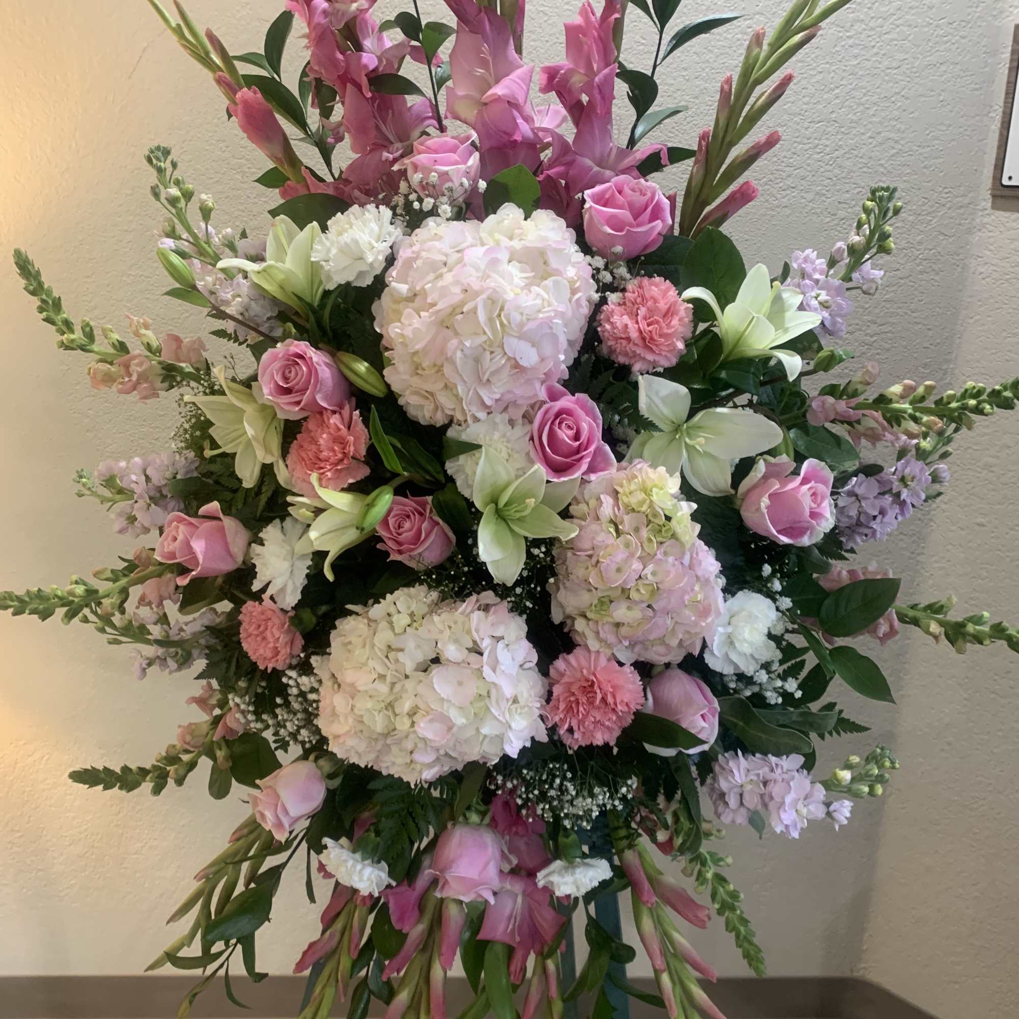 Pink roses, lilies, and more come together for a blushing pink standing