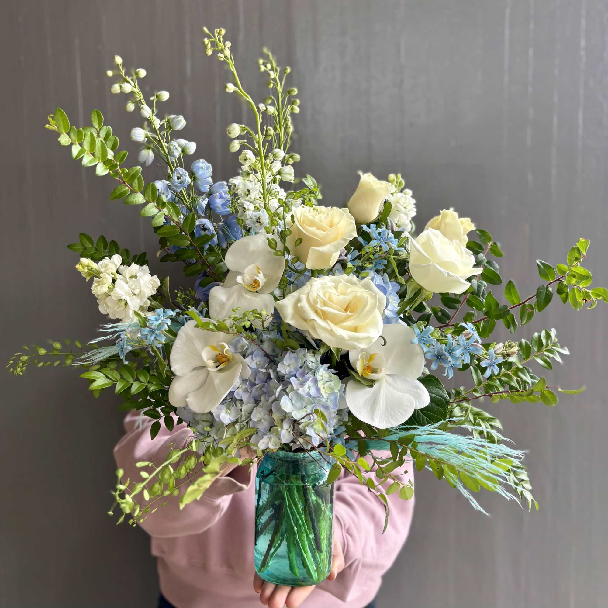 Aqua tones are refreshing in this arrangement. Featuring blue hydrangeas and delphiniums