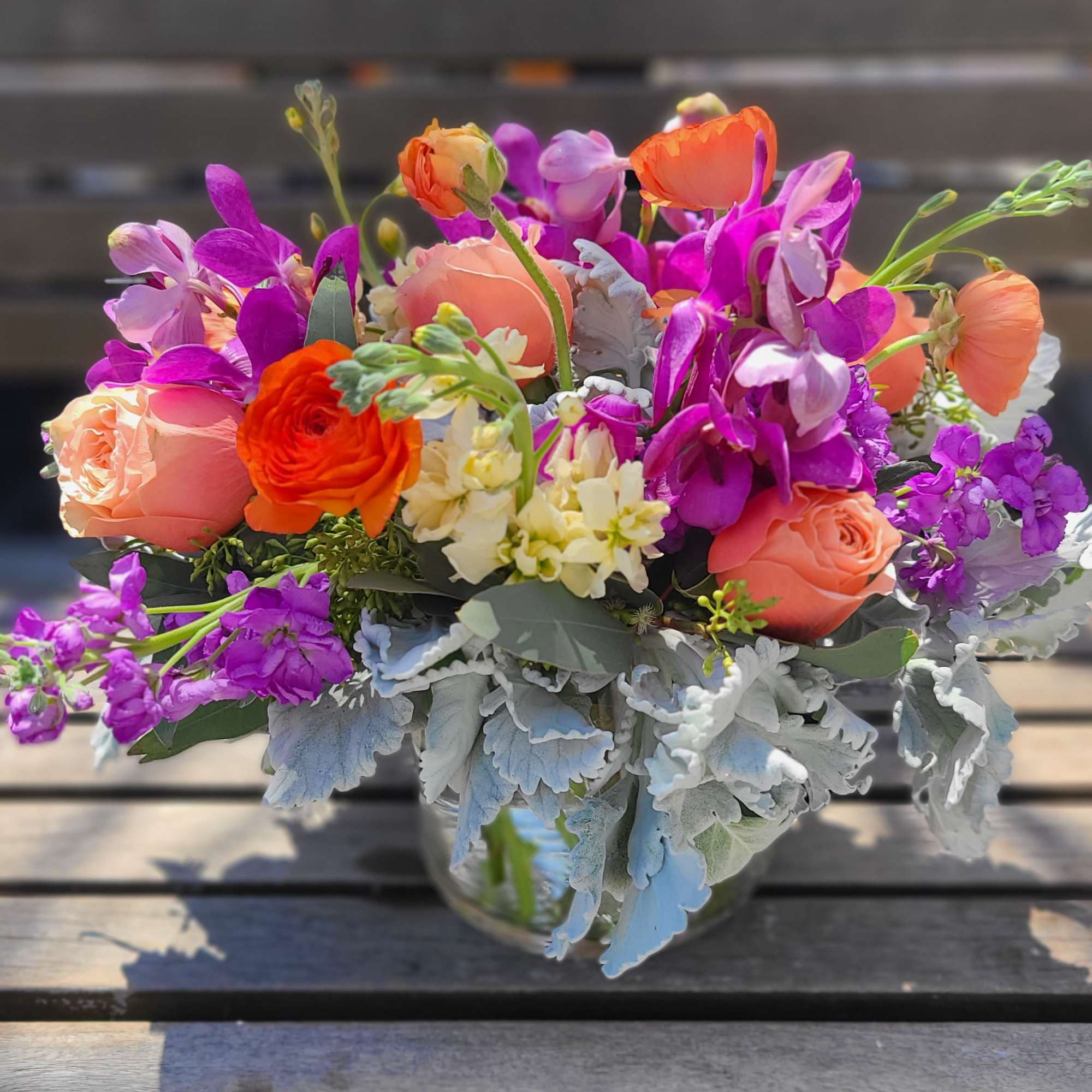 This arrangement is a new design using peaches, oranges and purples. The