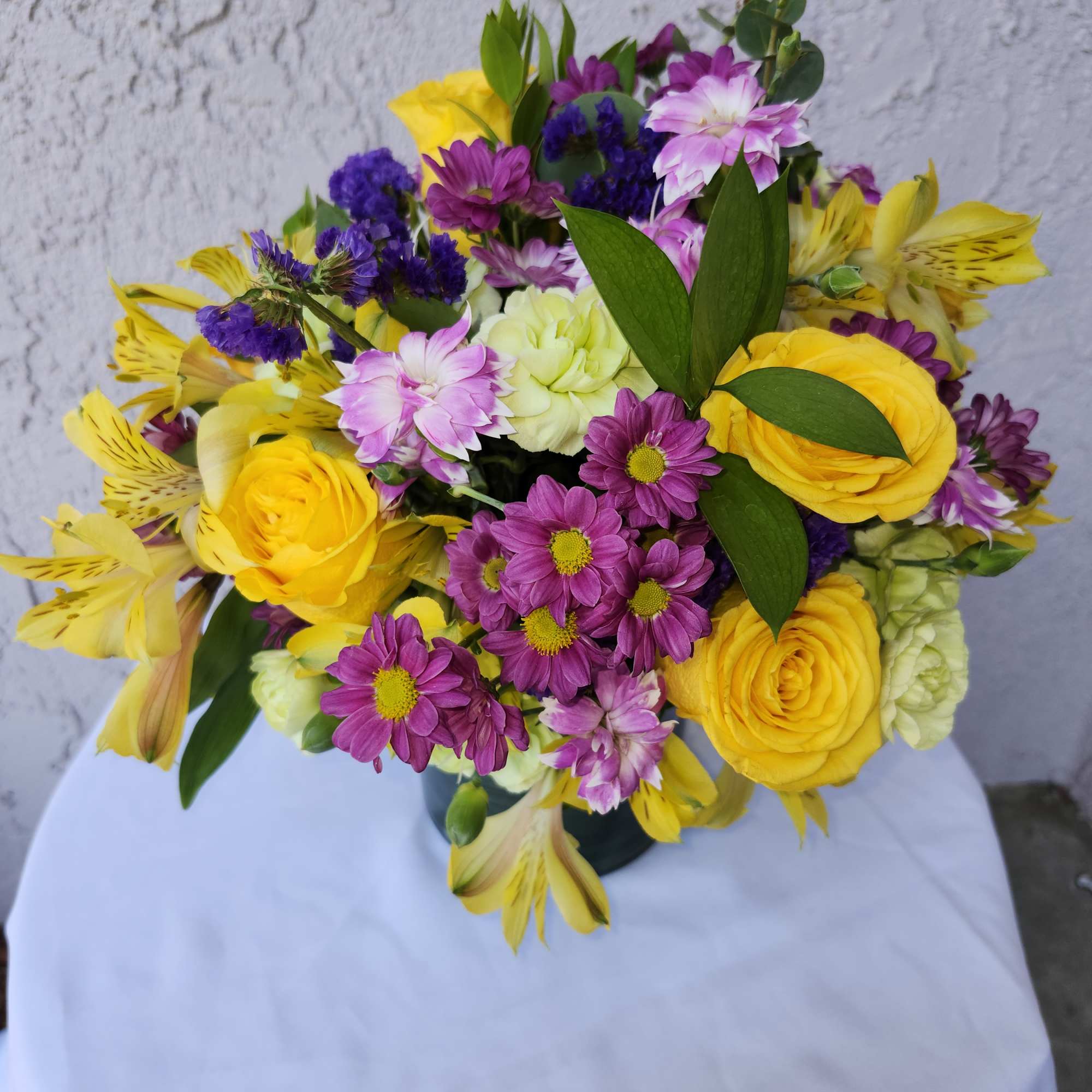 Vibrant purples and yellows bouquet of roses, alstermeria, daisies, carnations for summer