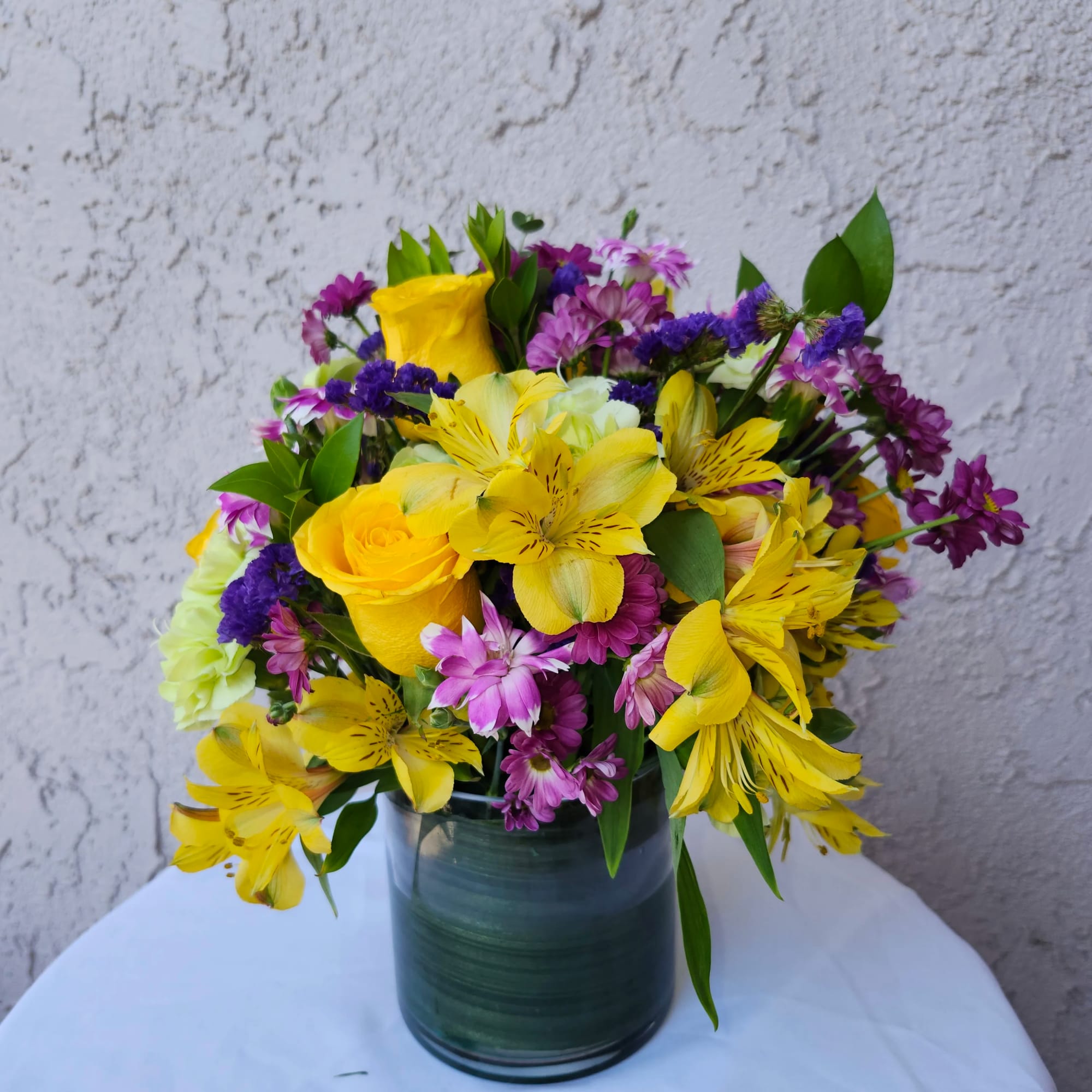 Vibrant purples and yellows bouquet of roses, alstermeria, daisies, carnations for summer