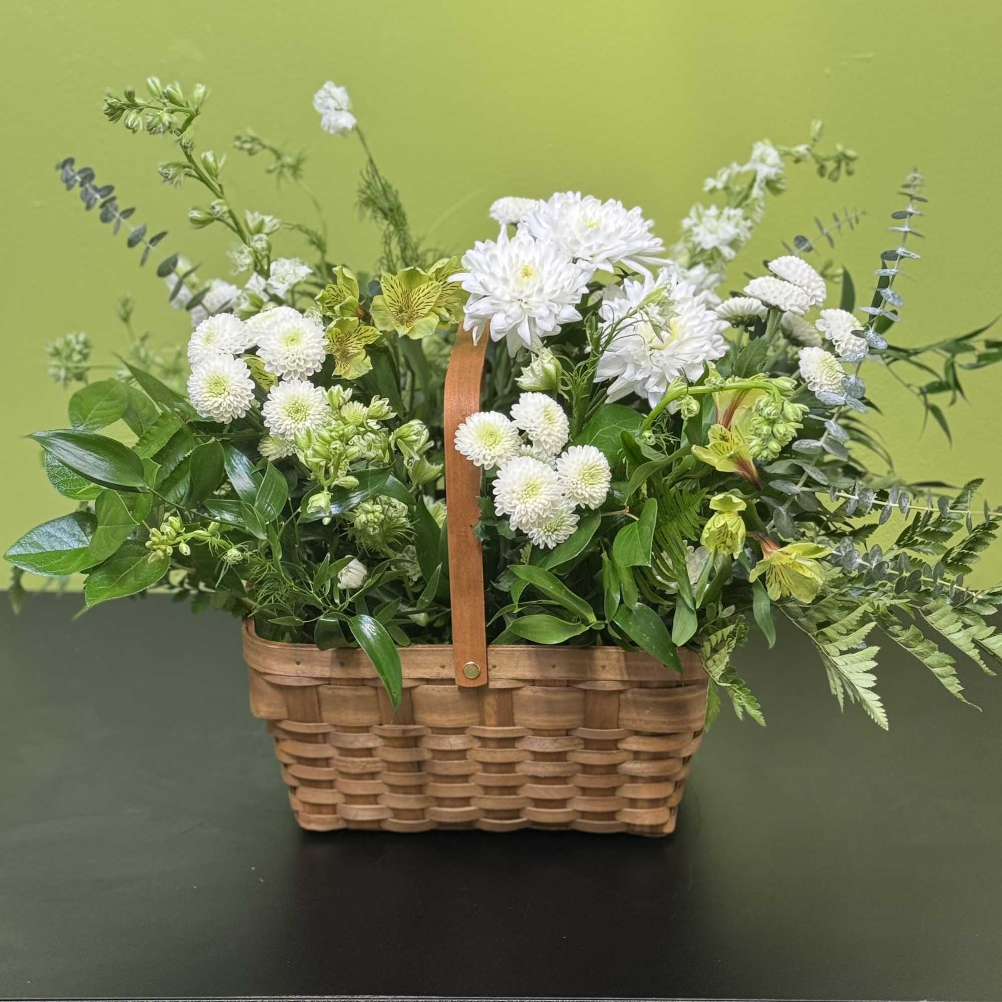 A peaceful white and green basket featuring white daisy mums and white