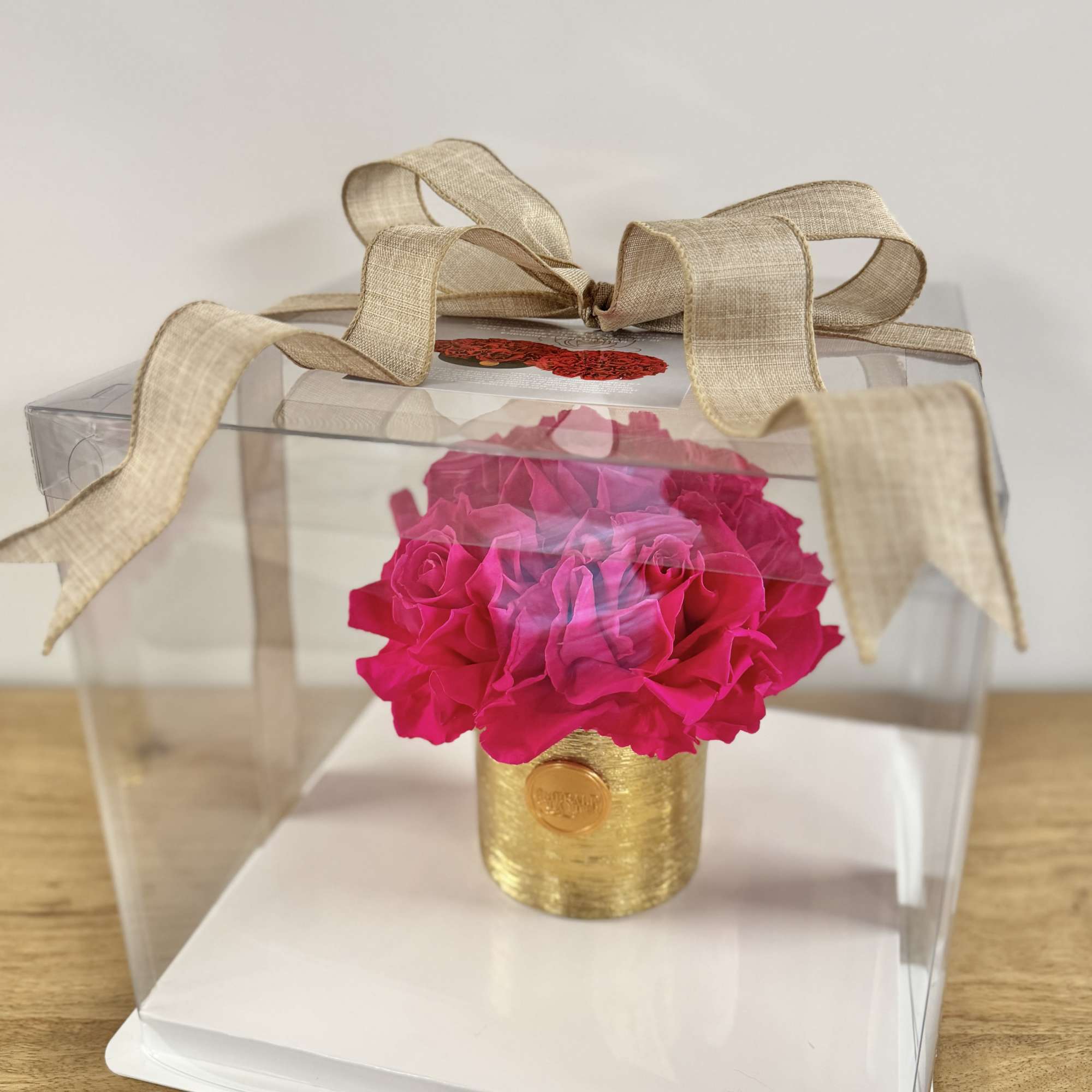 Six vibrant preserved fuchsia roses, thoughtfully arranged in a luminous gold vessel.