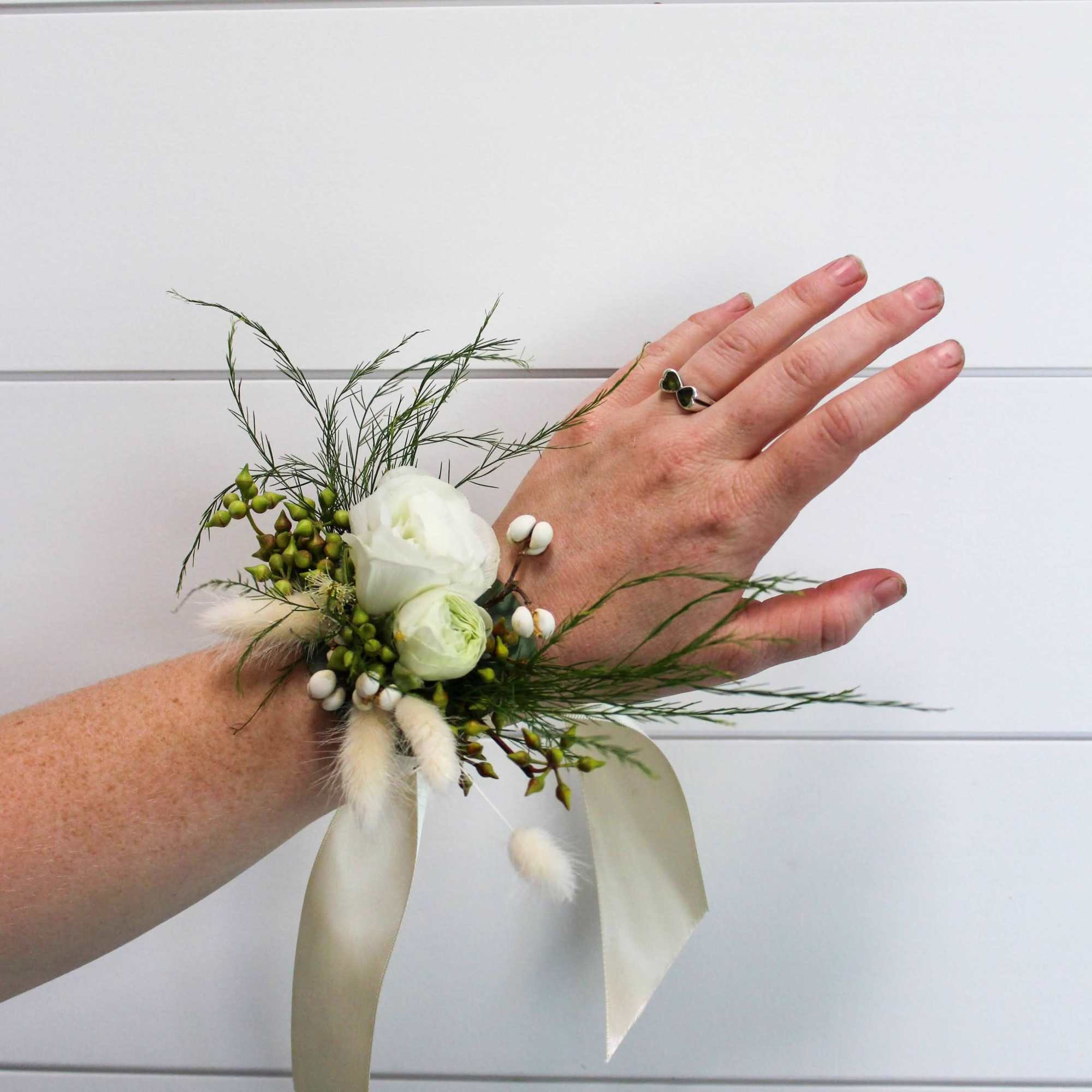 A corsage made of white and green tones. Perfect for weddings, prom