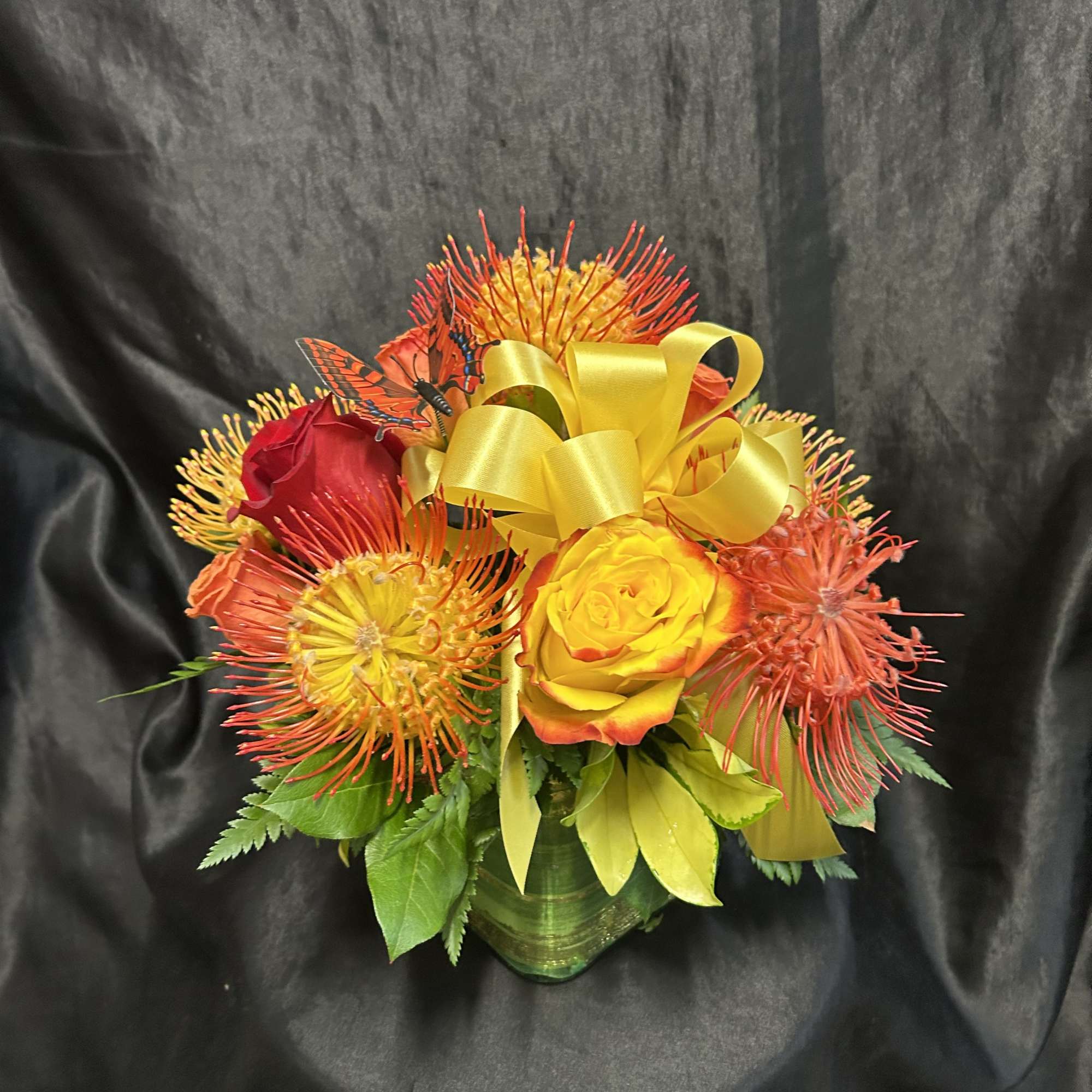 Vibrant sunset colors! Assortment colors of Roses, pincushions, with mixed greens. 