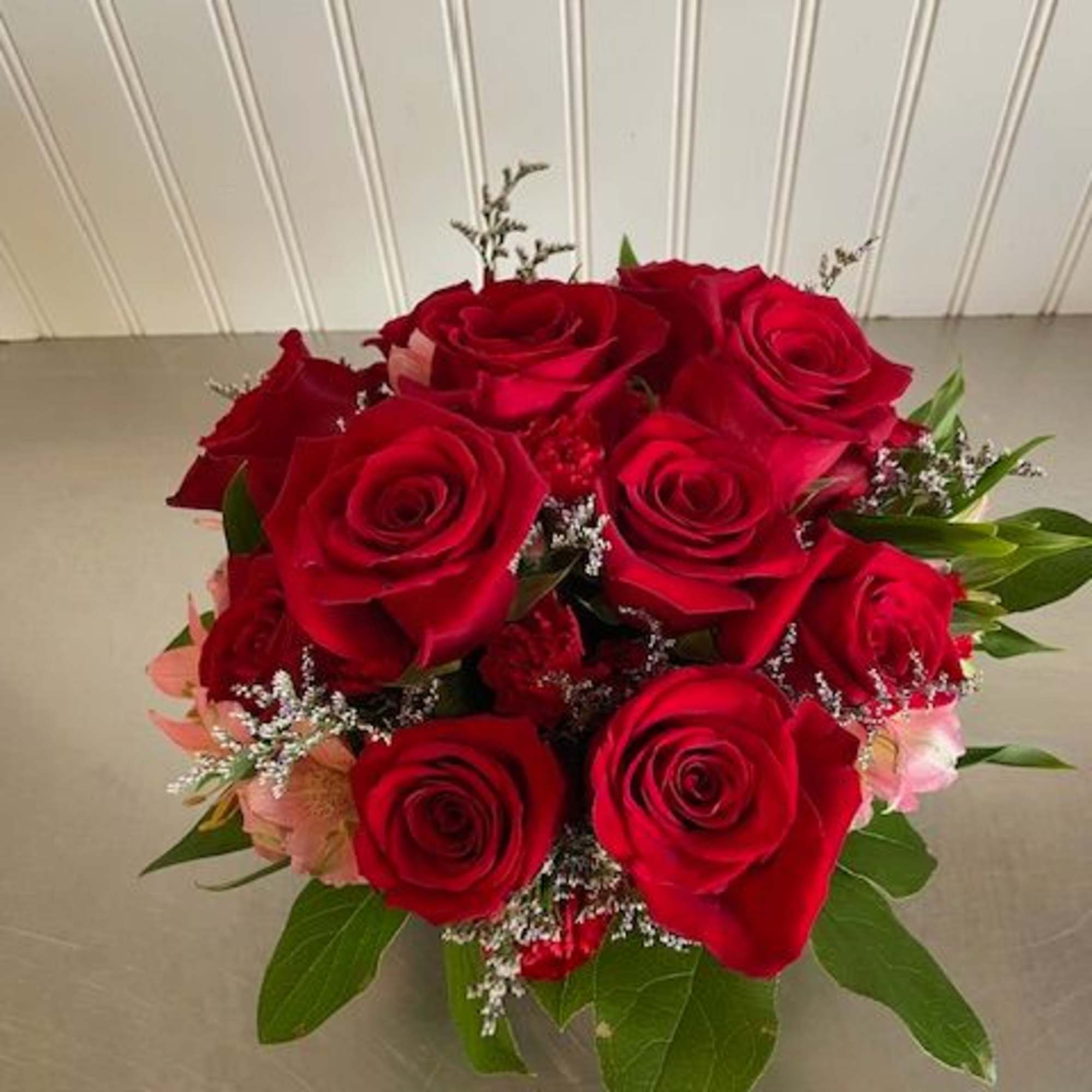 A dozen red roses accented with pink Alstroemeria and dotted with red