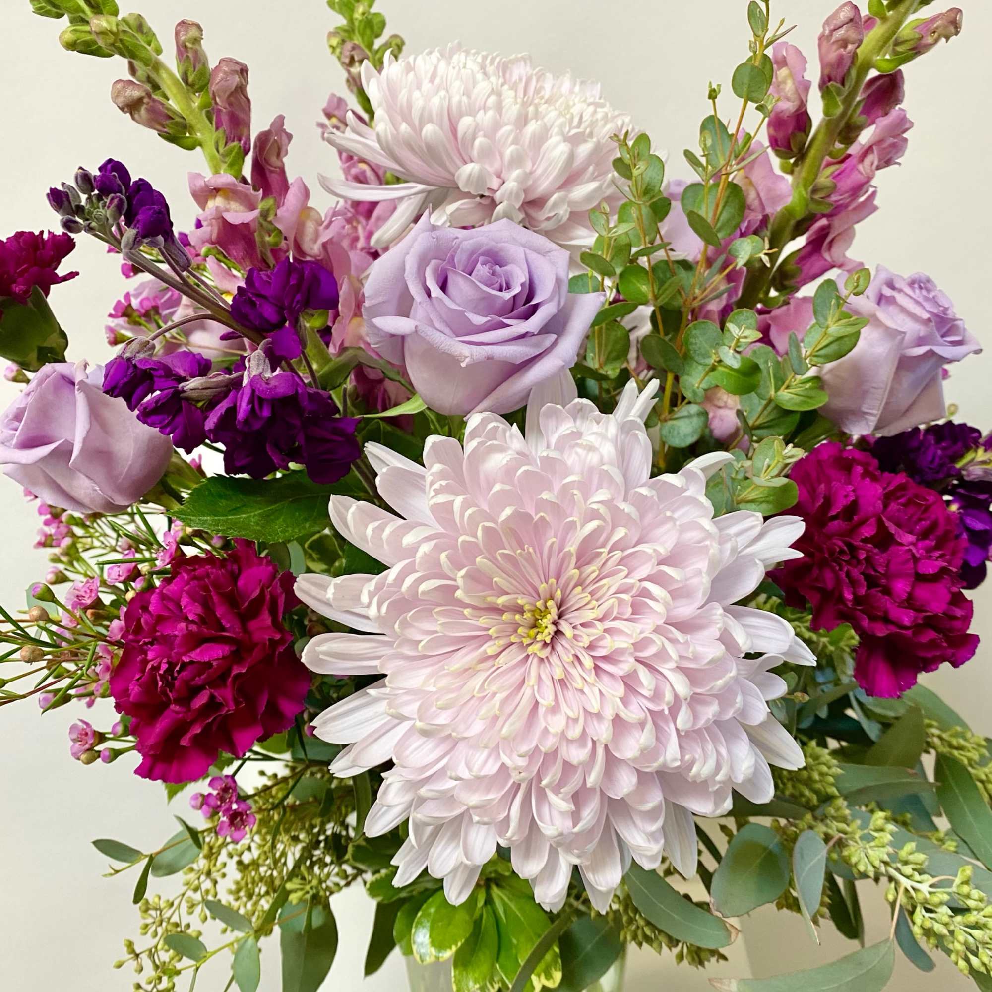 This Tall Purple Monochrome Arrangement includes Premium Greenery, Cremone Mums, Snapdragons, Stock