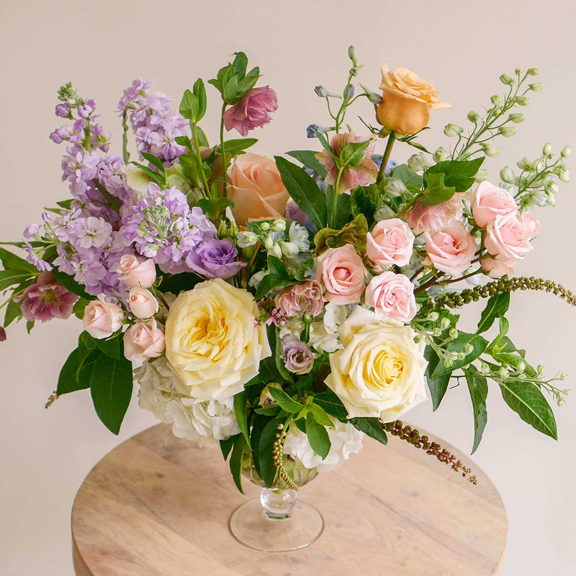 This lush arrangement features colorful pastel blooms such as roses, stock, delphiniums