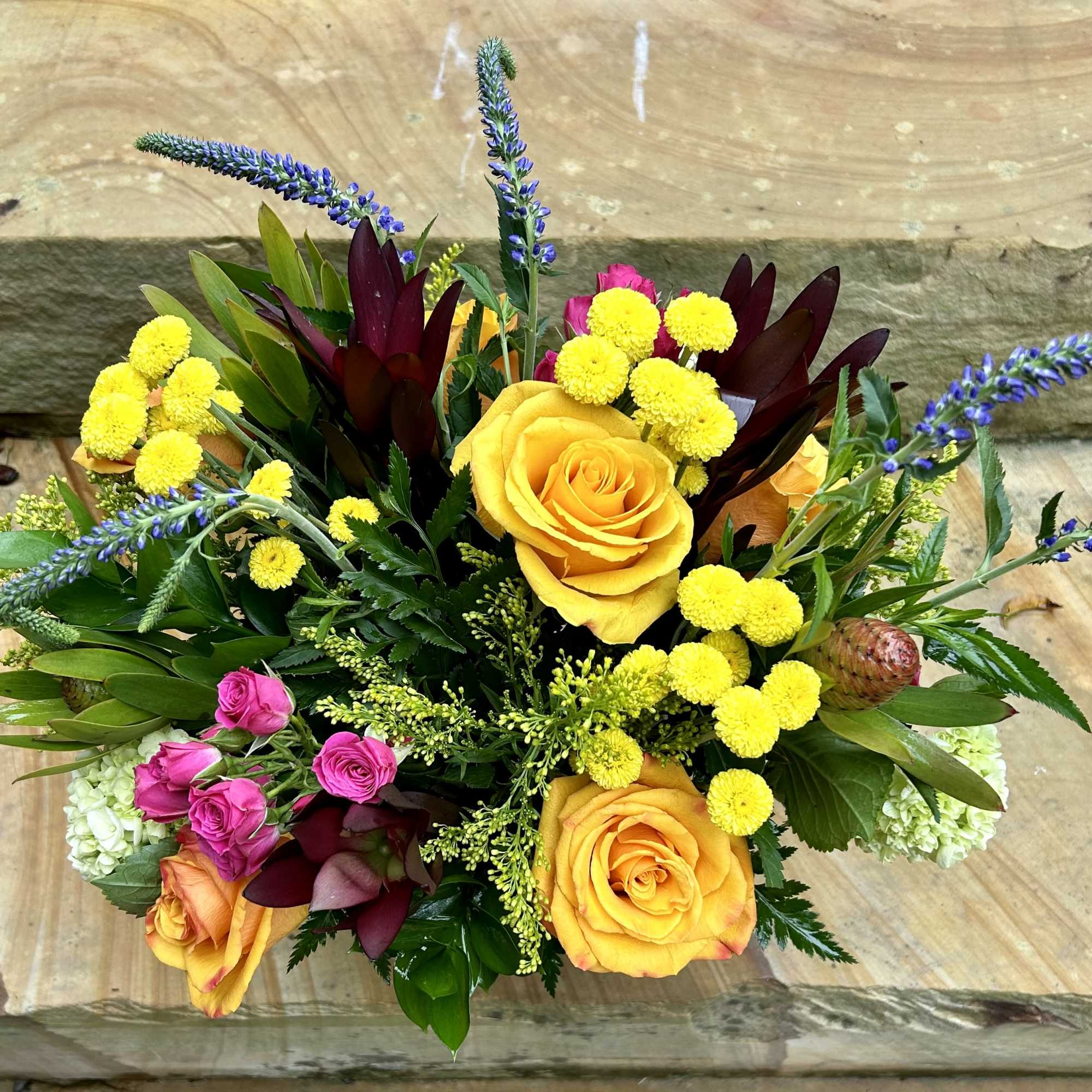 A fresh and airy arrangement of yellows, orange, pinks, purples, reds and