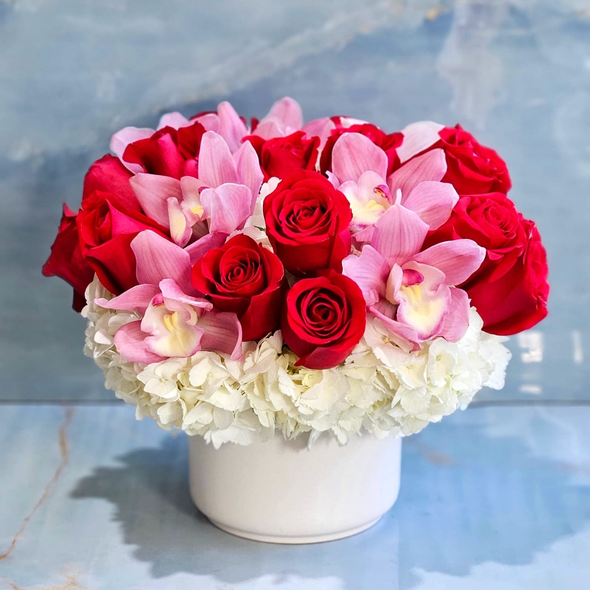 Roses, Hydrangeas, and Cymbidium Orchids in a ceramic vase. 