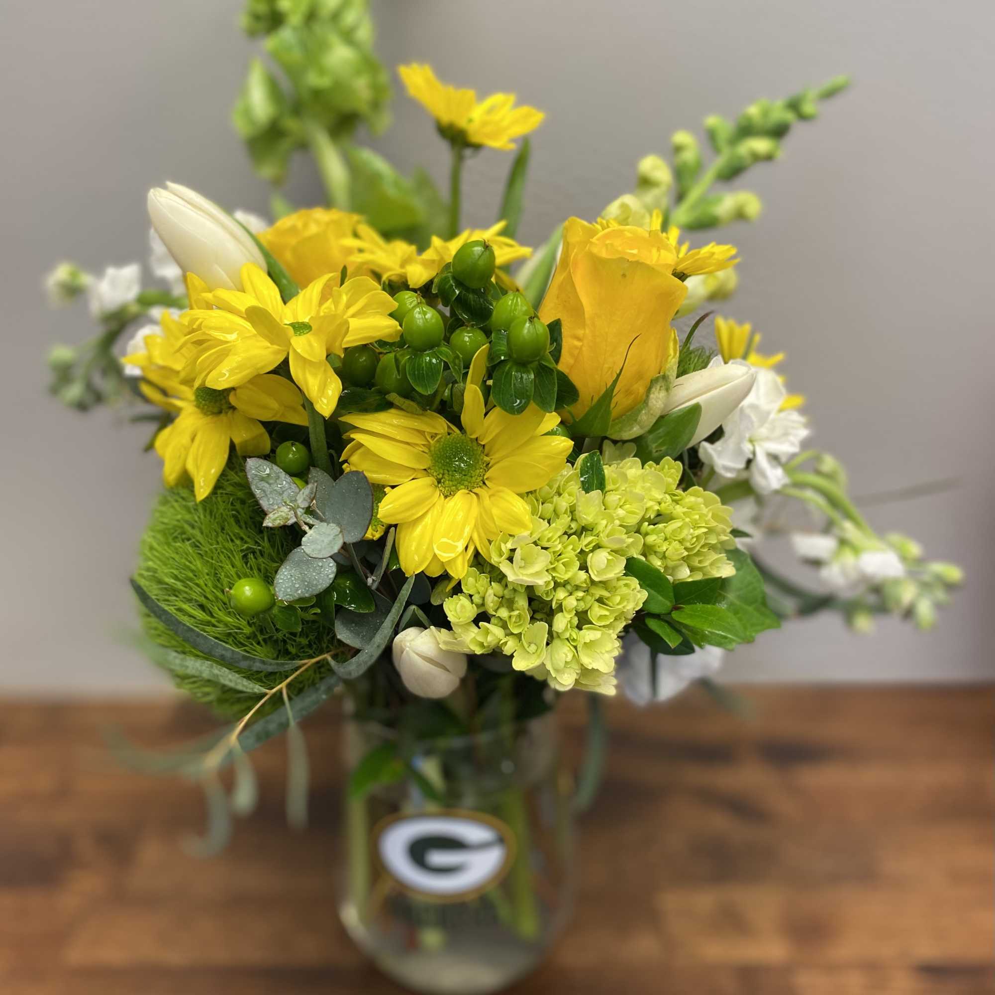 A stemless Packers Glass wineglass, filled with a combination of green and