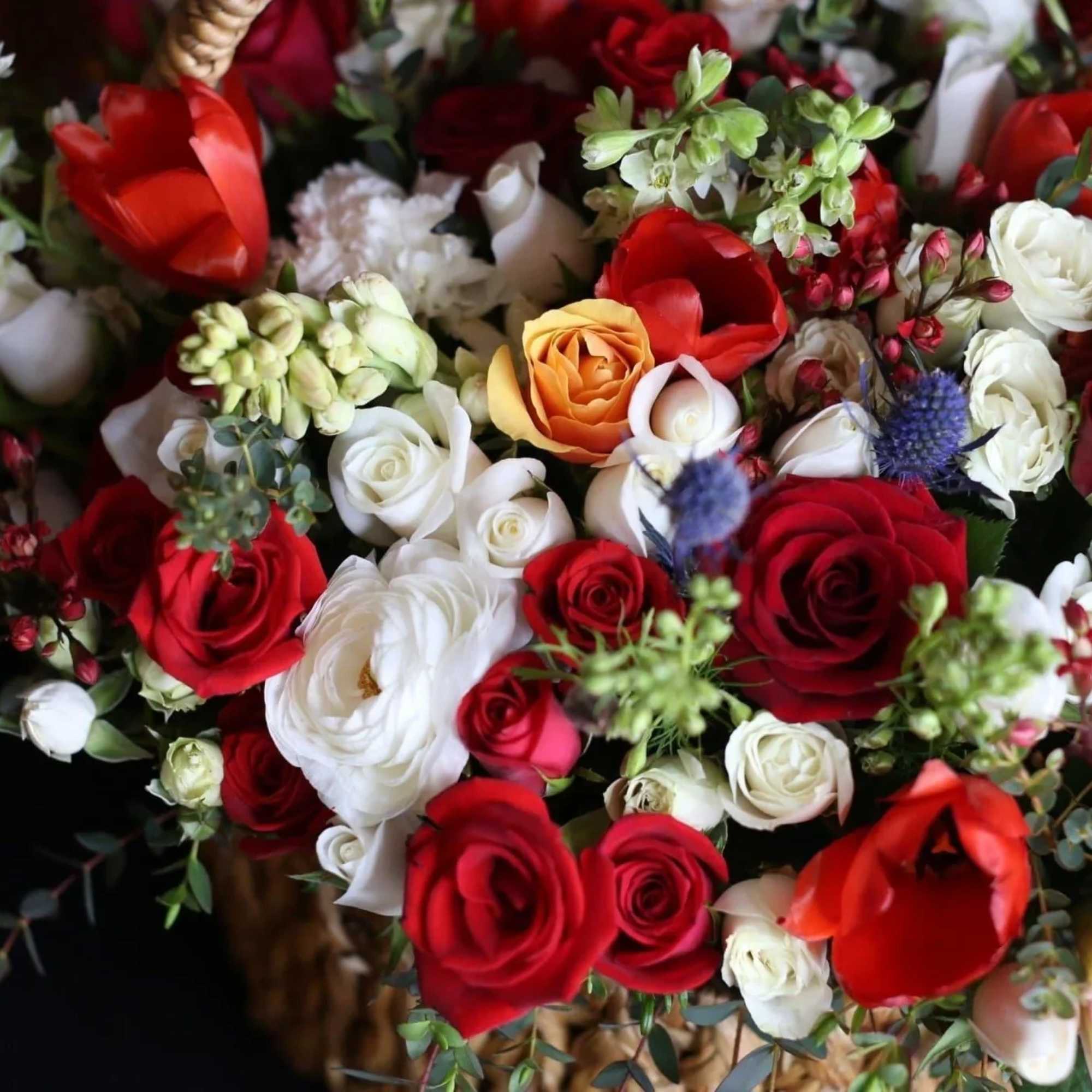 The basket of roses, ranunculus, delphinium, thistle and tulips flowers with Baby