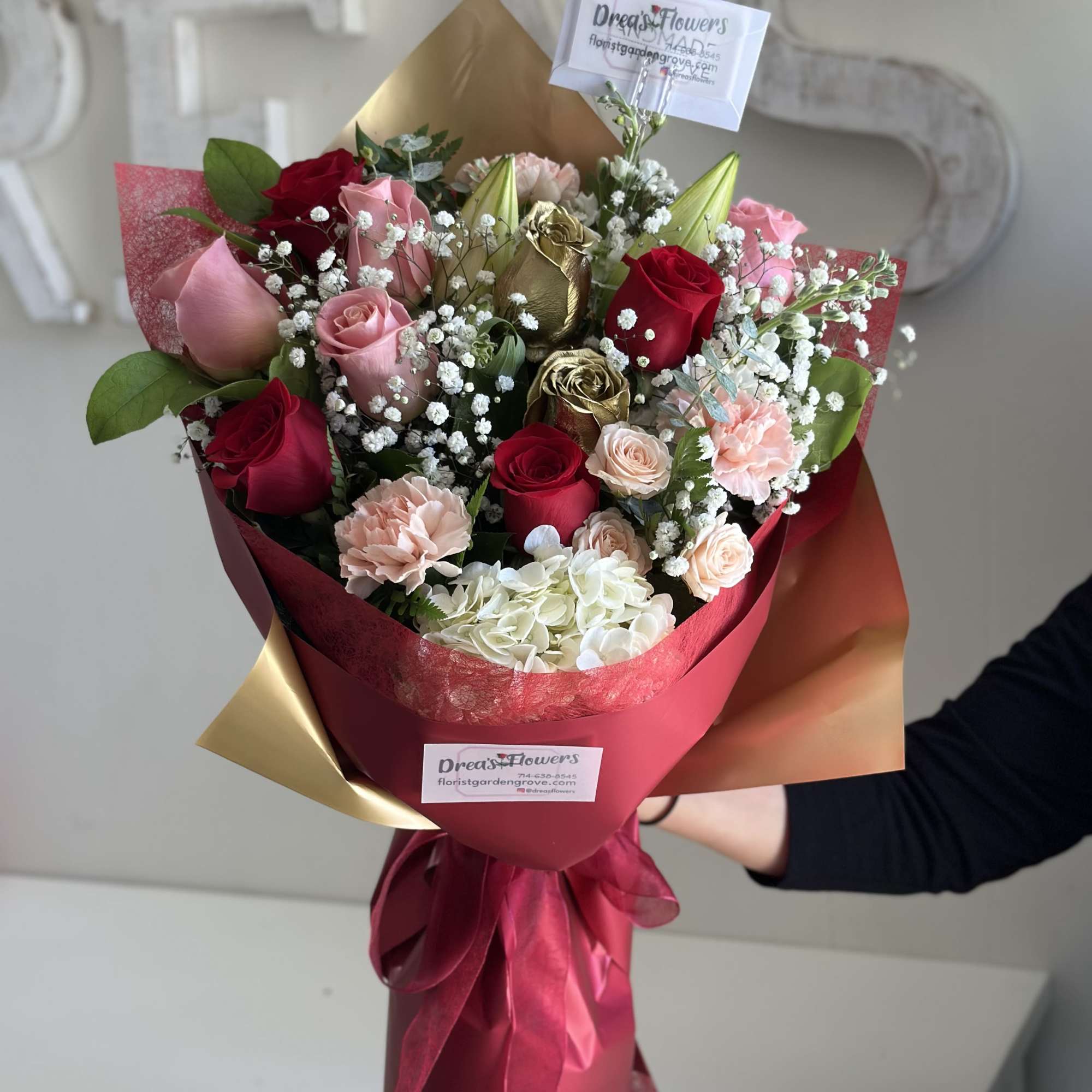 Handheld arrangement, white, pink and gold colored flowers. 
Arrangement does not include