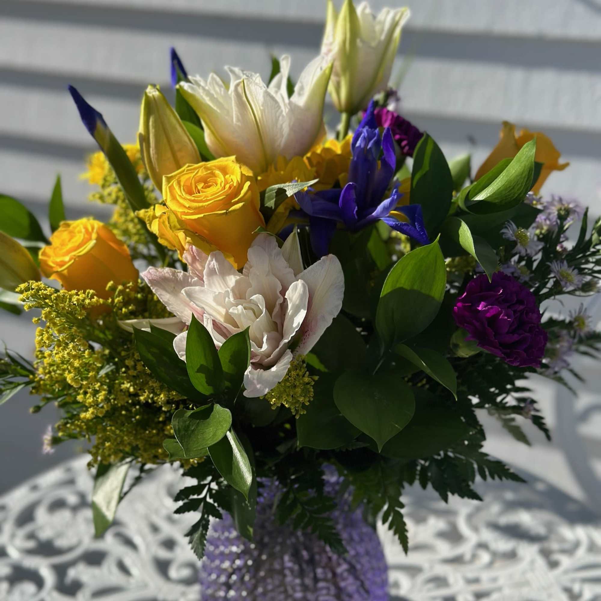 Pink Lilies, Yellow roses daisies, iris, purple carnations and solidago arranged in