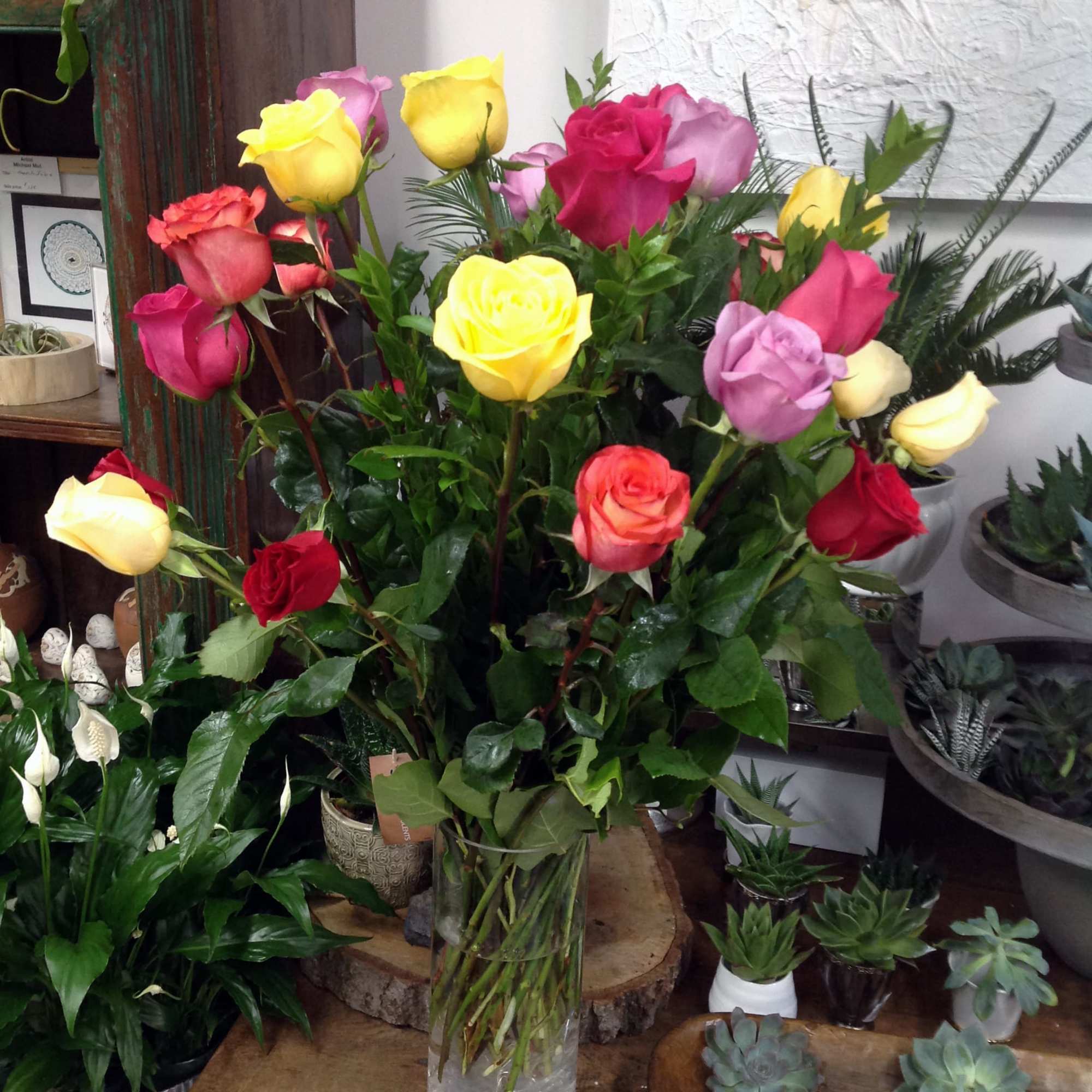A cheerful arrangement contains one dozen long stem-colored roses in a cylinder