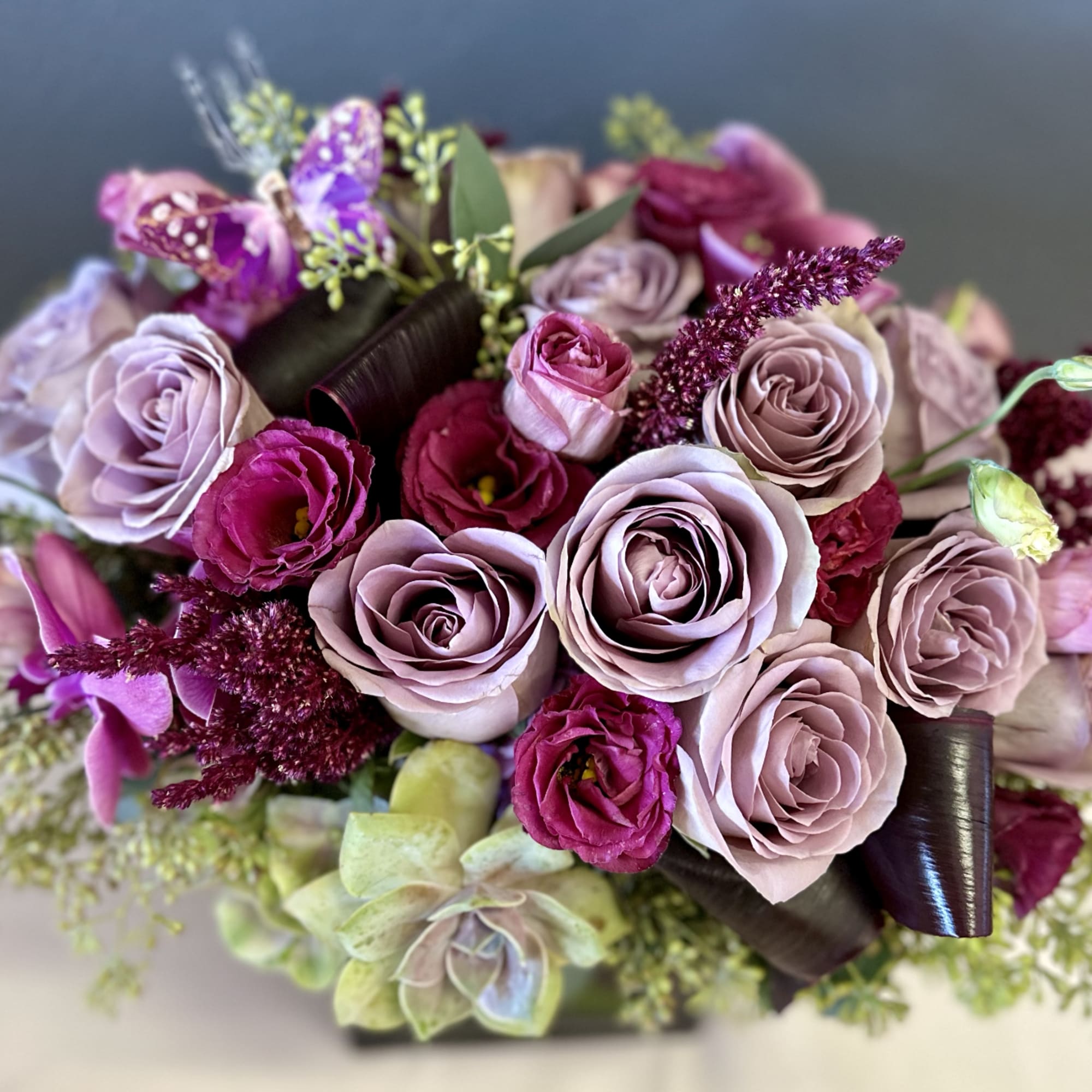 A beautifully designed abundance of Amnesia roses, plum lisianthus, amaranth, eucalyptus, and