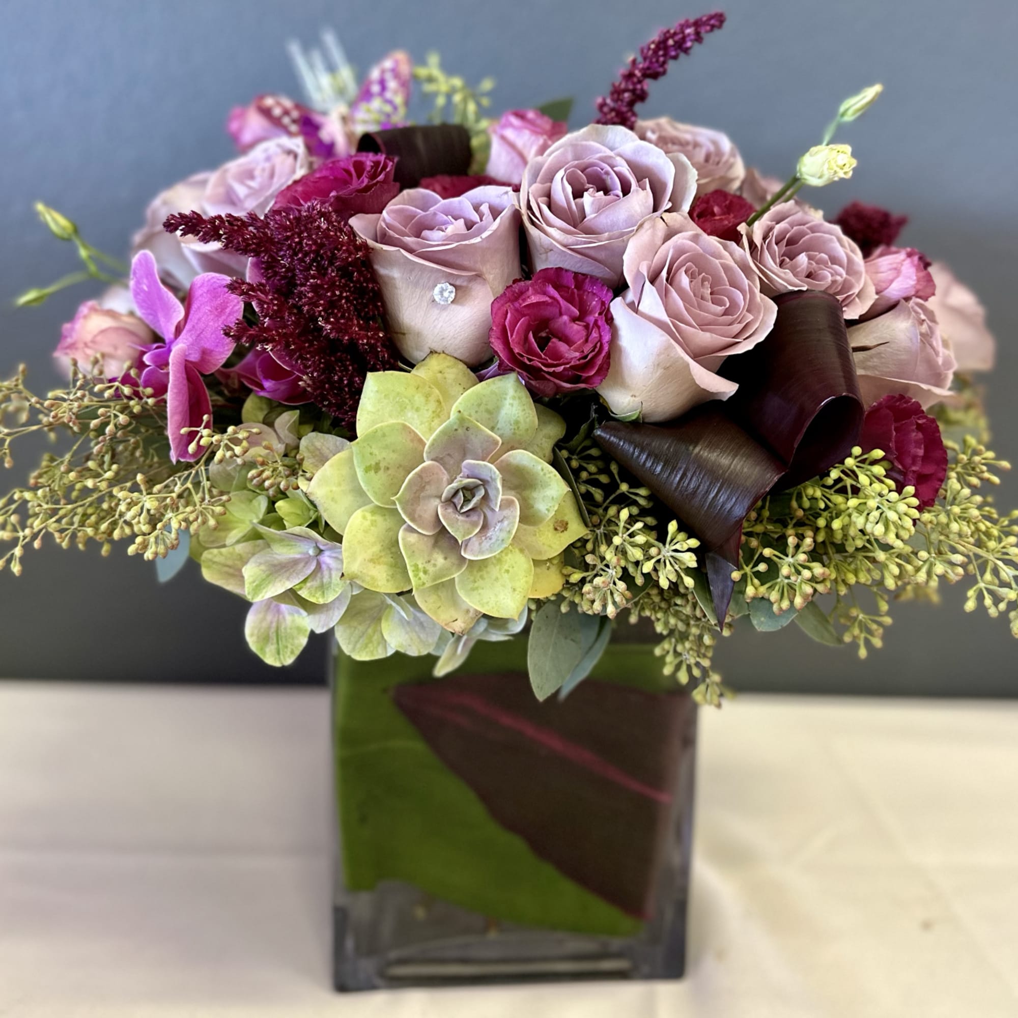 A beautifully designed abundance of Amnesia roses, plum lisianthus, amaranth, eucalyptus, and