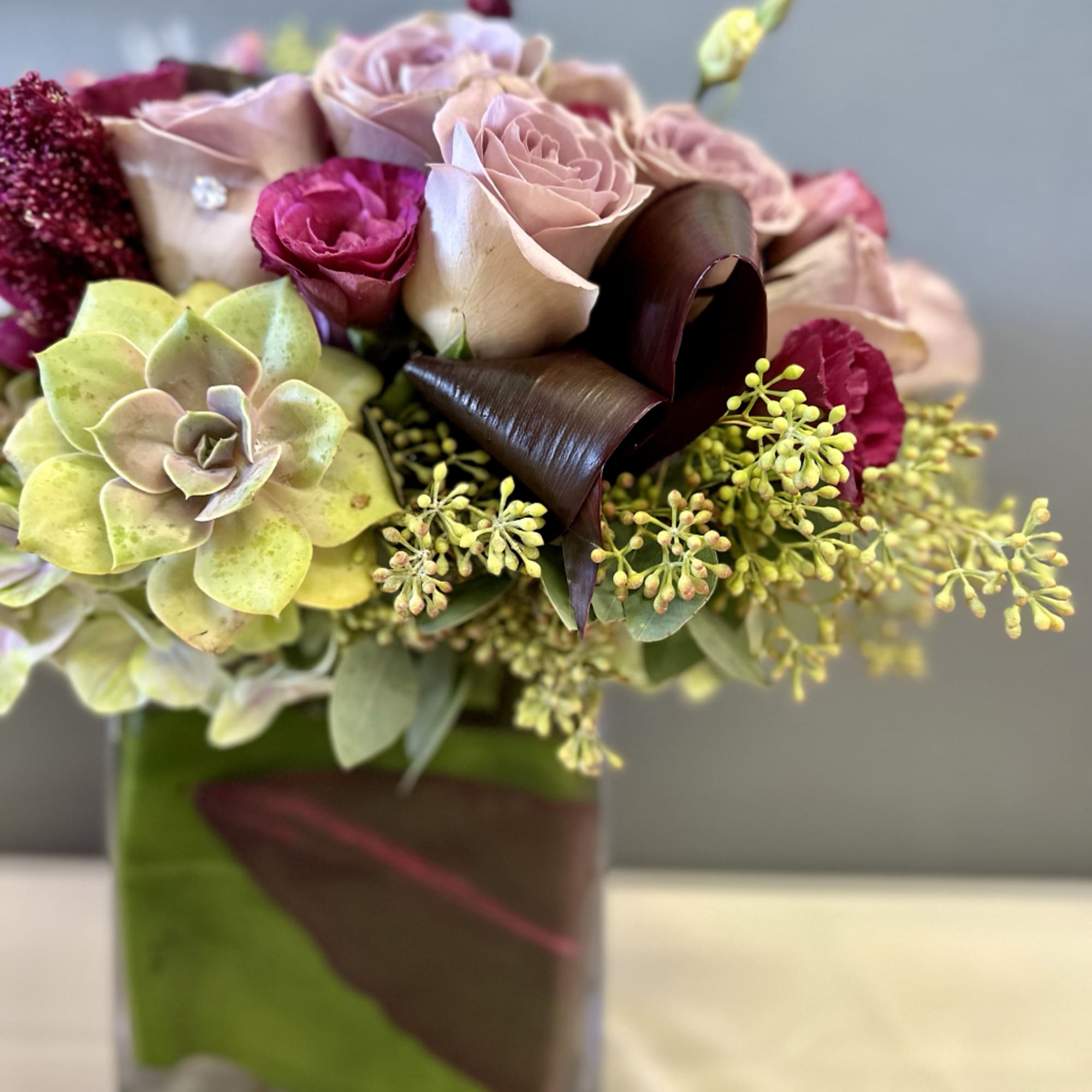 A beautifully designed abundance of Amnesia roses, plum lisianthus, amaranth, eucalyptus, and