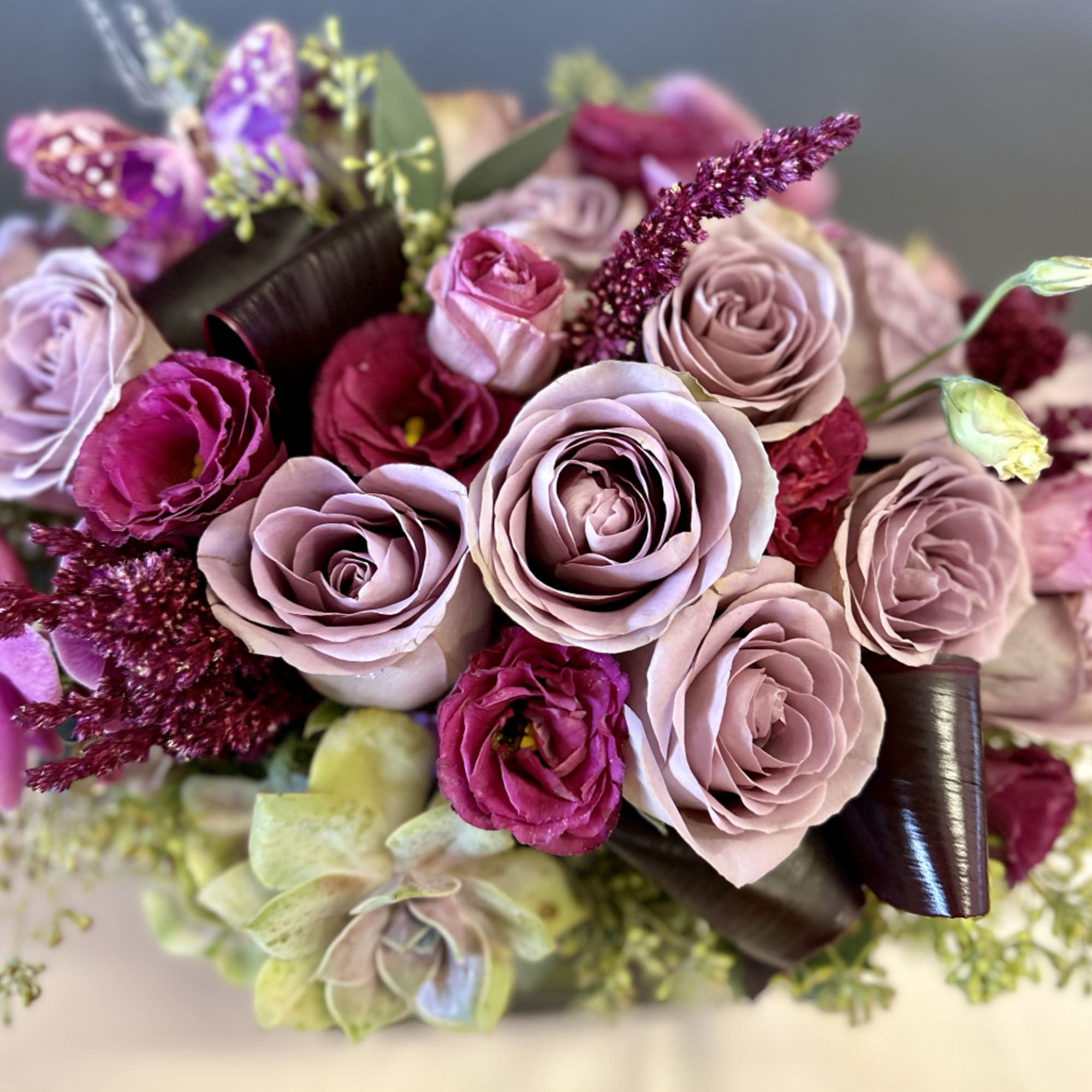 A beautifully designed abundance of Amnesia roses, plum lisianthus, amaranth, eucalyptus, and