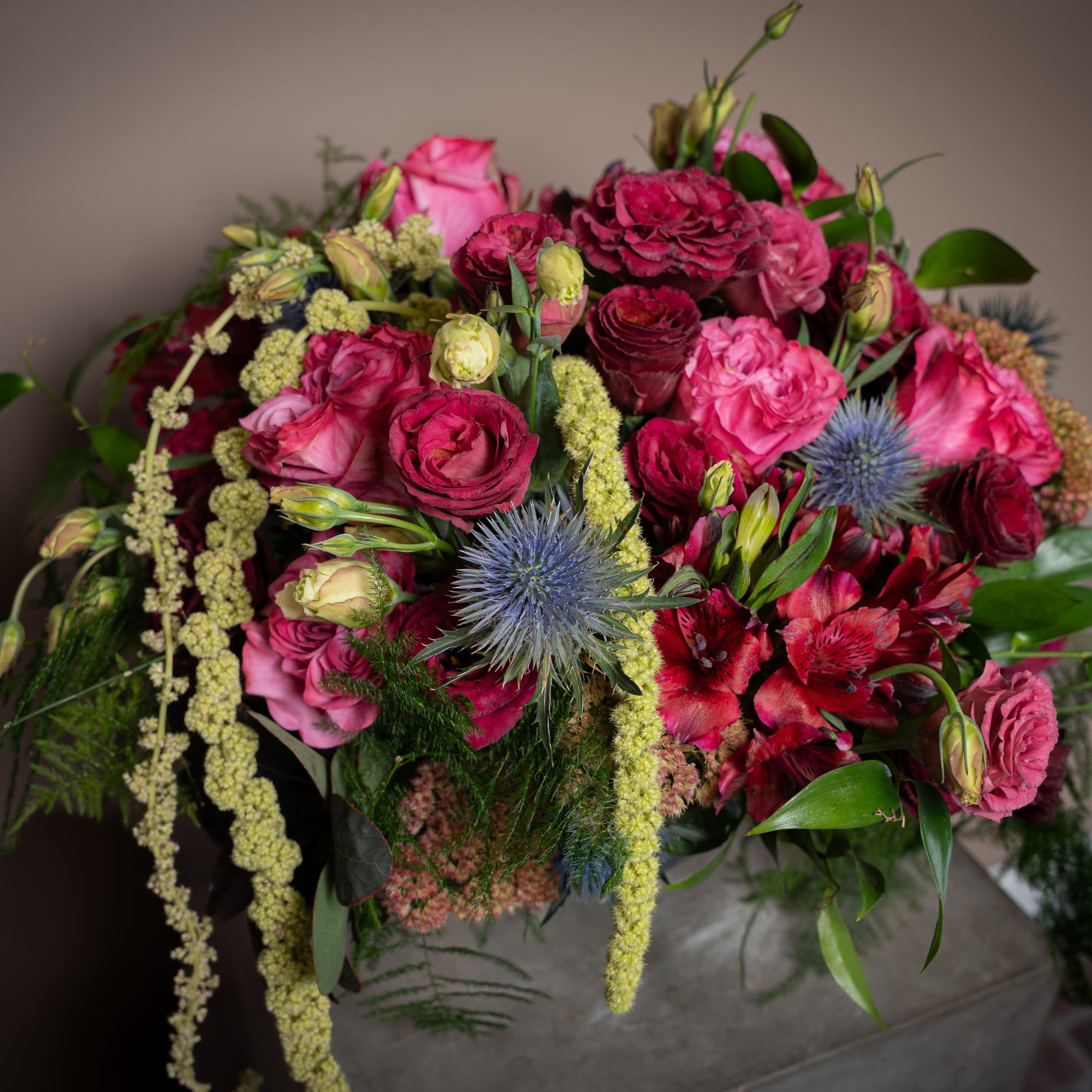 Pink and jewel-toned colors come together with amaranthus, thistle, rice flower, and