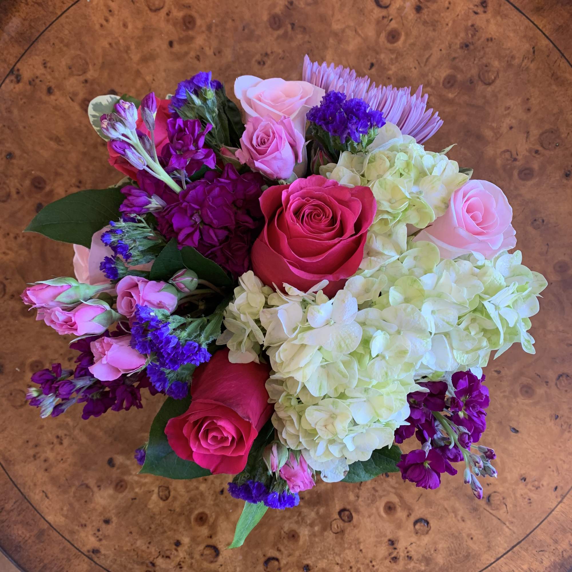 This arrangement includes hot pink roses, pink roses, green hydrangea, lavender spray