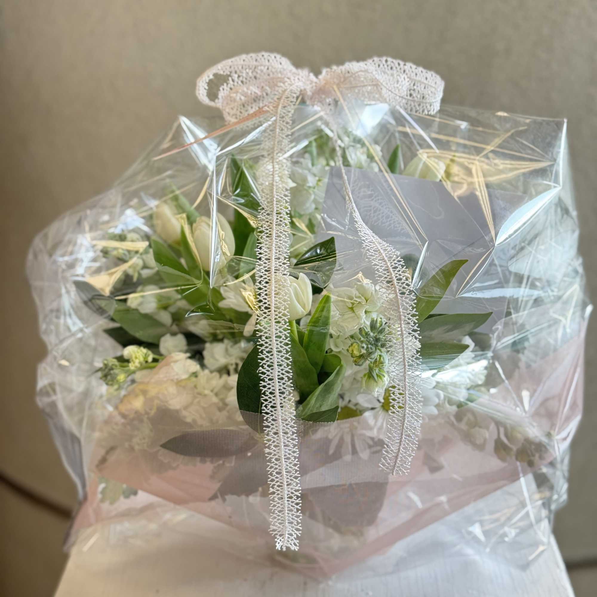 A fresh and timeless white floral arrangement featuring soft tulips, delicate stock