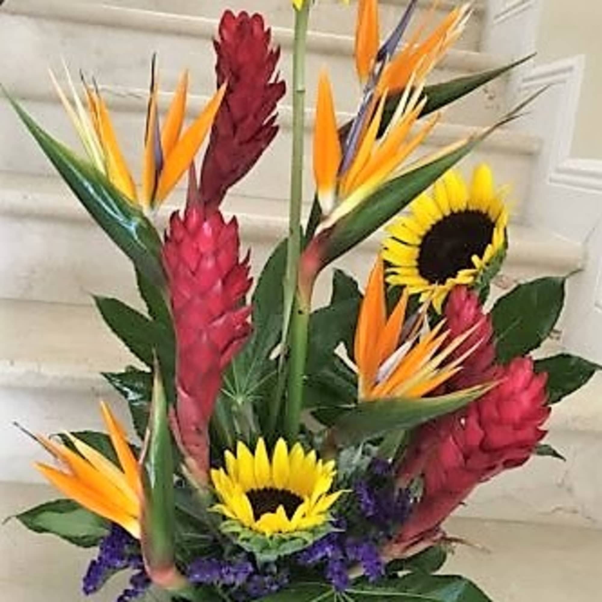Tropical flowers as shown arranged in a vase. The quantity of flowers