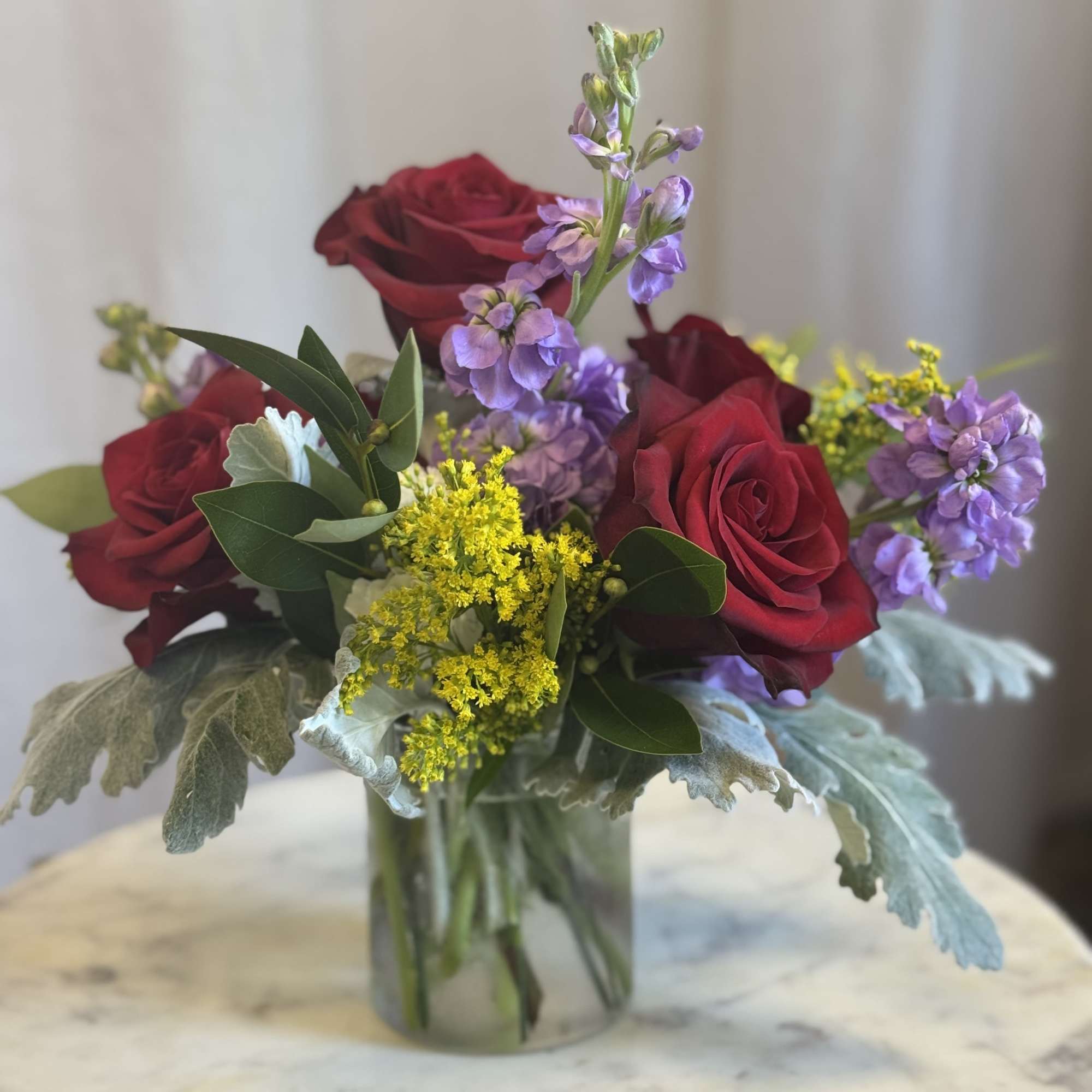 A soft yet striking floral design featuring rich red roses paired with