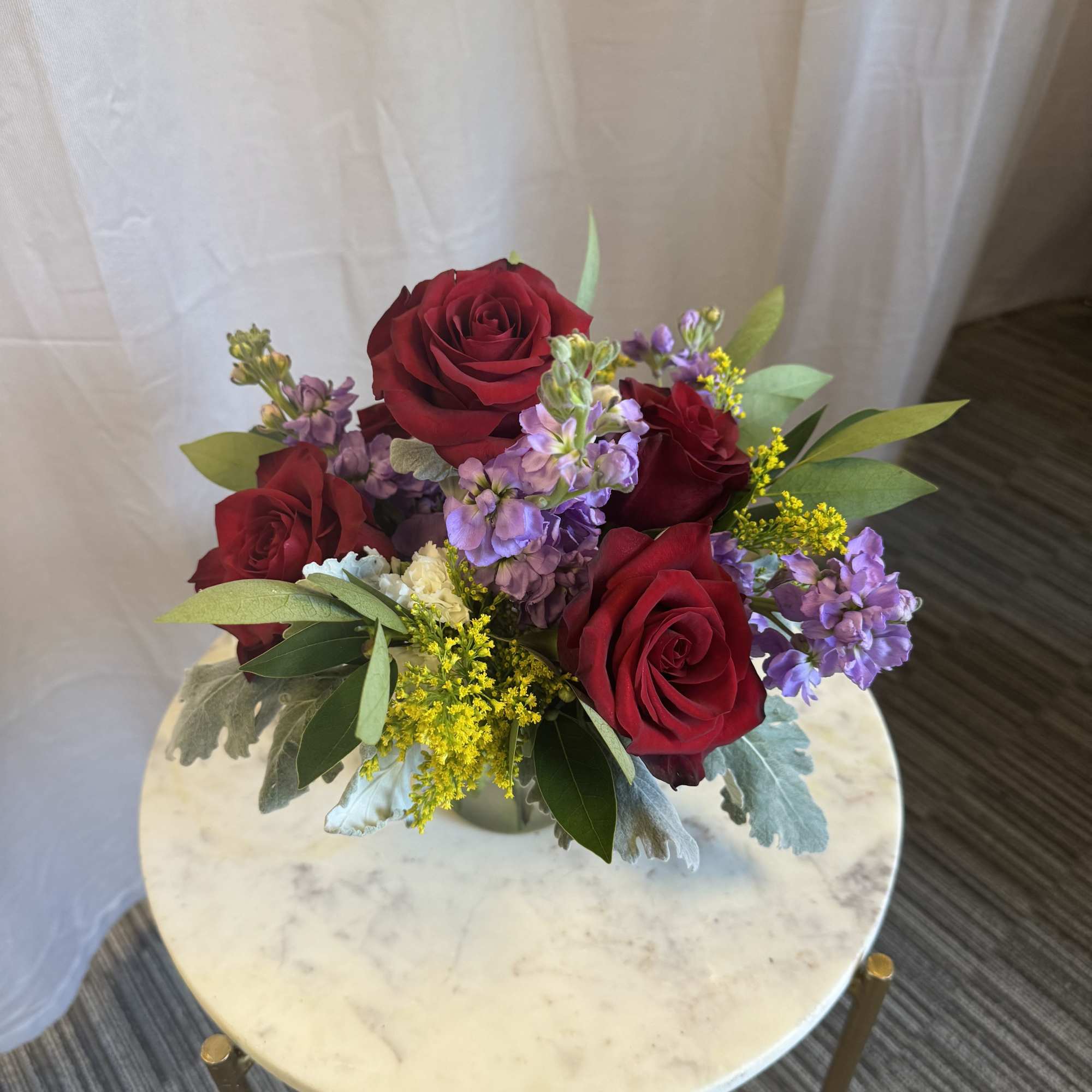 A soft yet striking floral design featuring rich red roses paired with