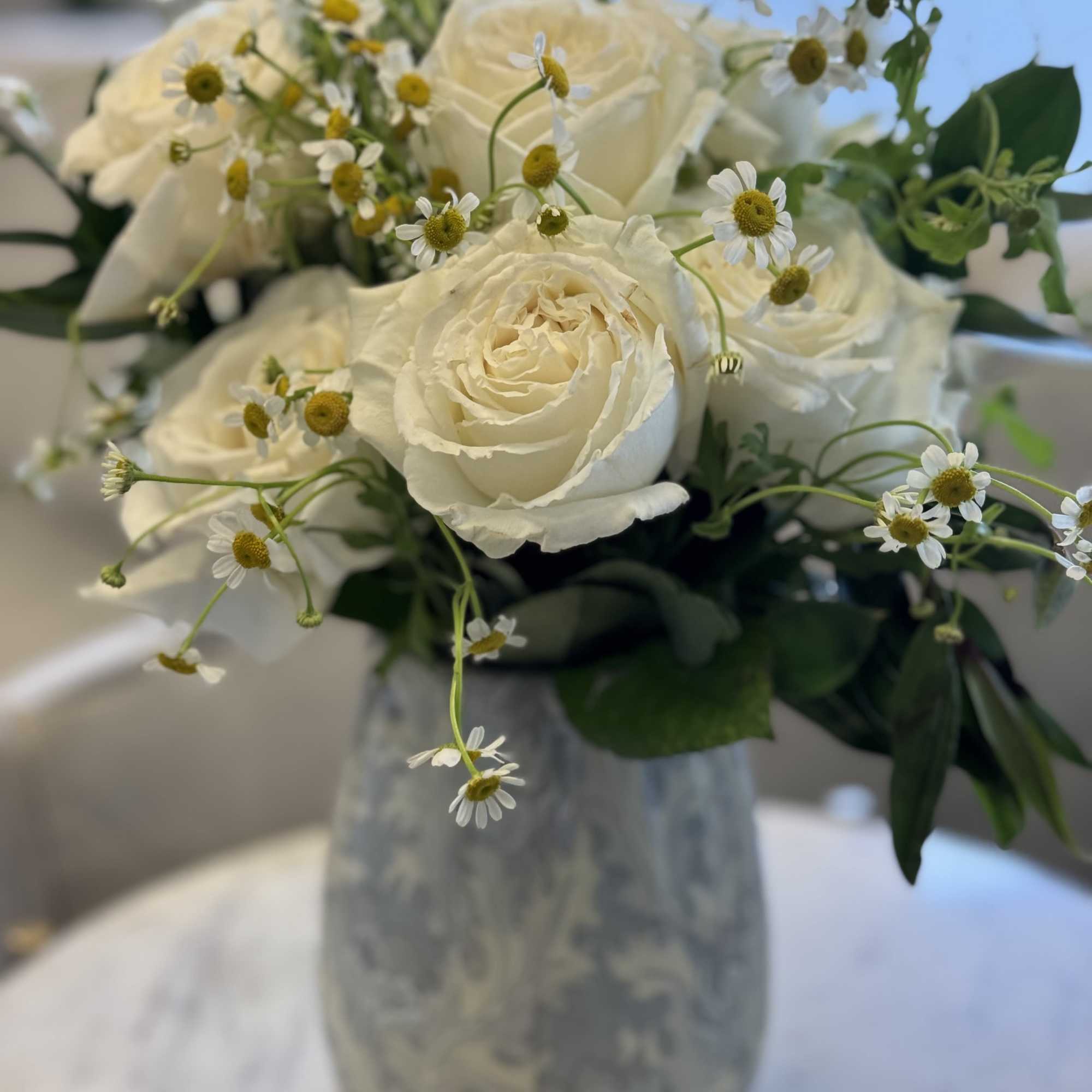 A fresh and elegant arrangement featuring creamy white premium roses accented with
