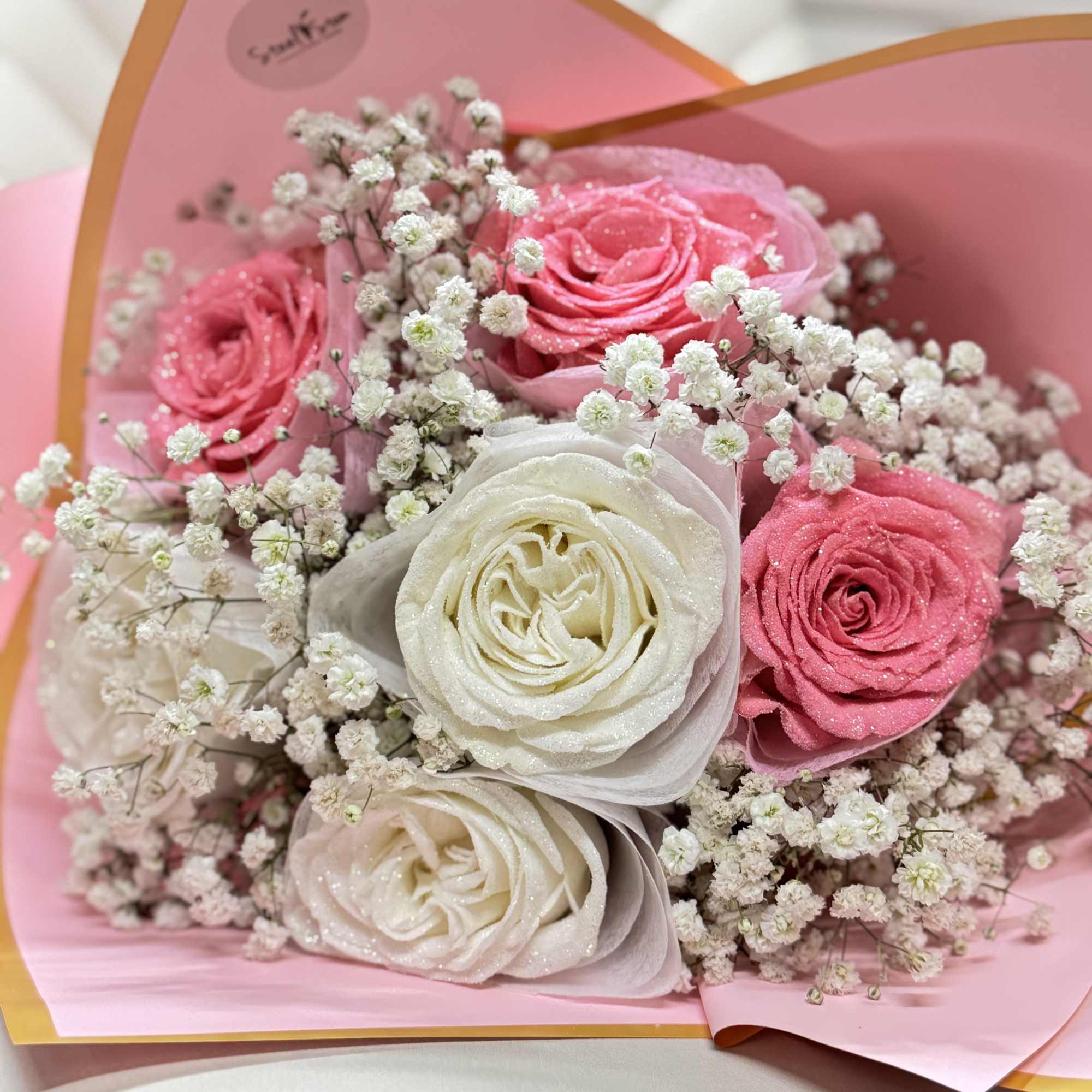 The pink and white glitter roses with gypsophila, tied together with pink