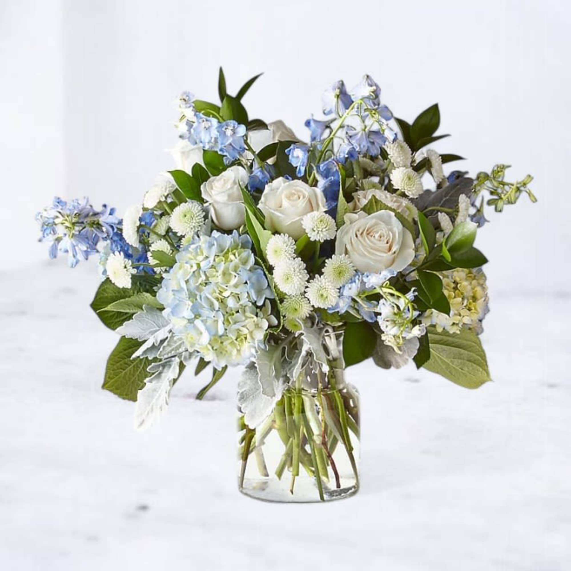 Blue Harbor is a softly layered arrangement of ivory roses, airy blue