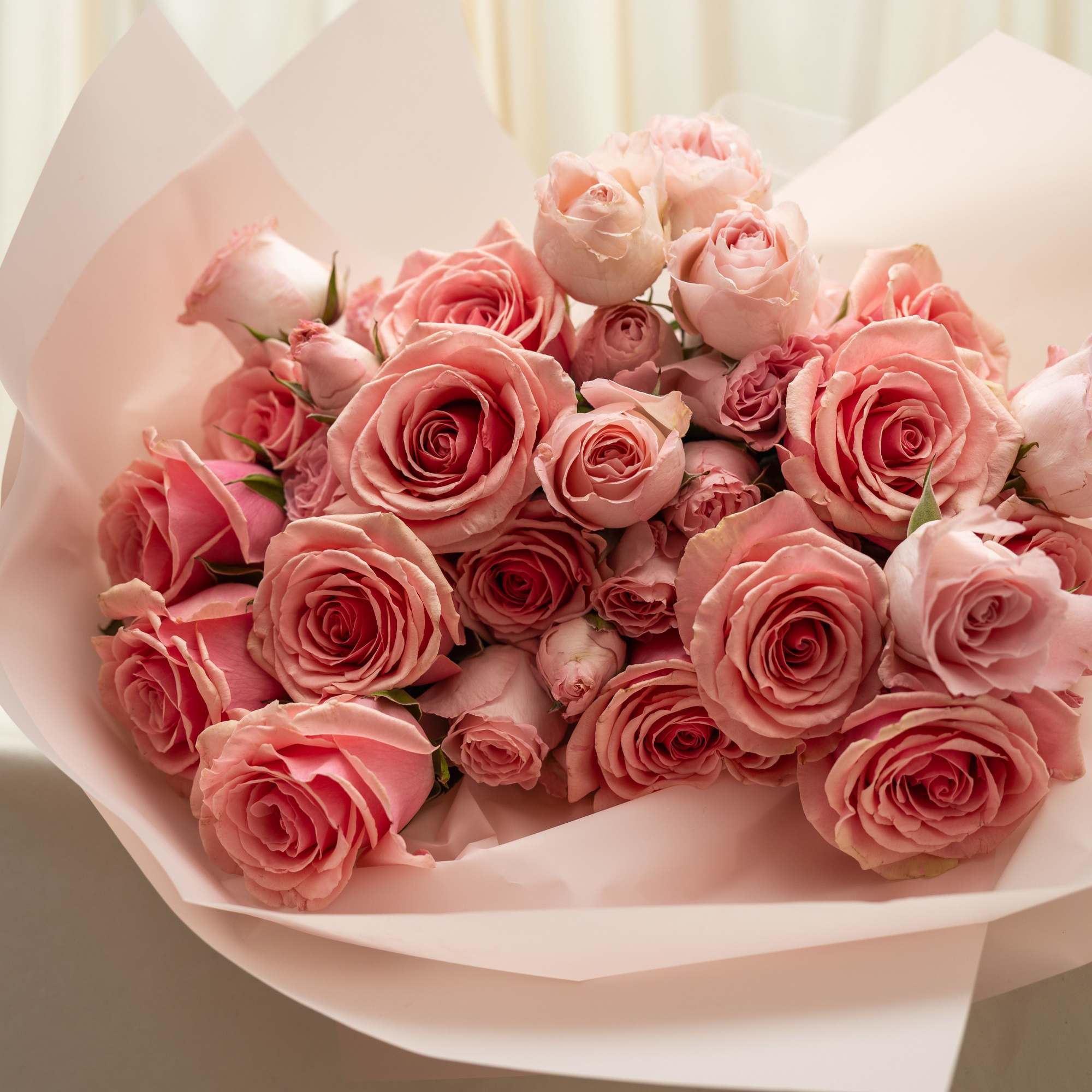 A romantic arrangement of pink roses and delicate spray roses, designed in